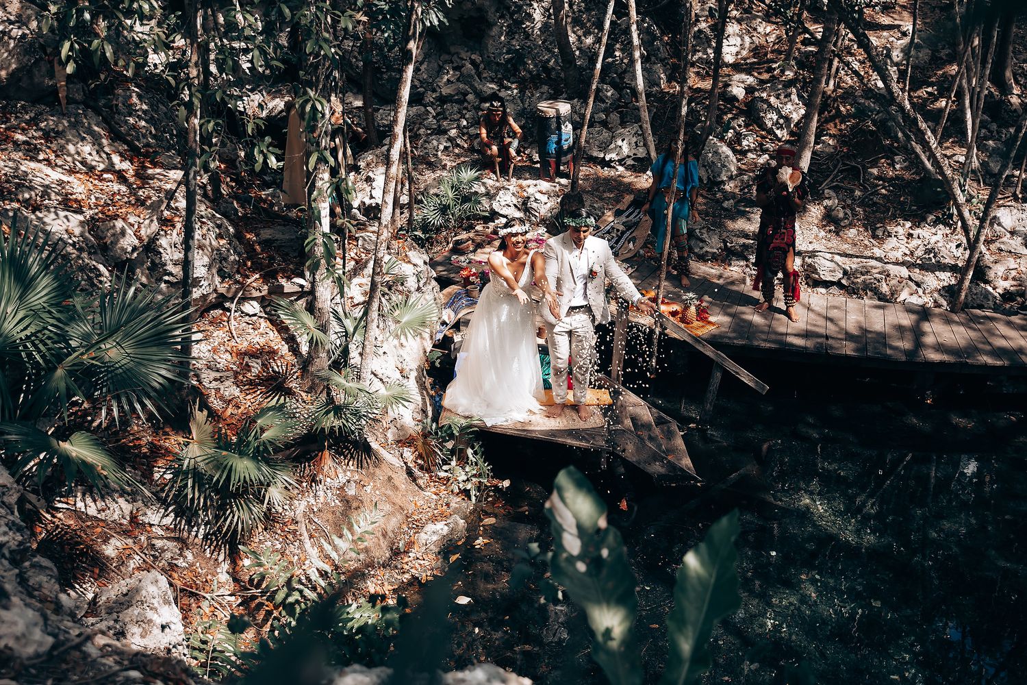 Wedding ceremony on wooden bridge in lush forest setting.