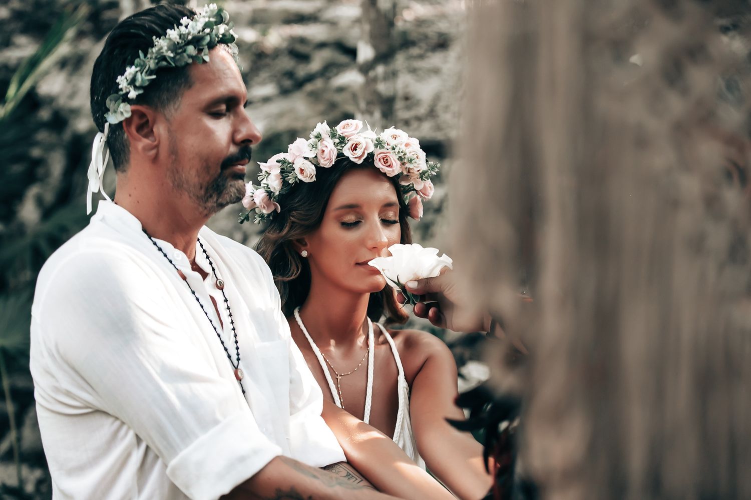 A couple performs a traditional ritual or ceremony in a natural, outdoor setting.
