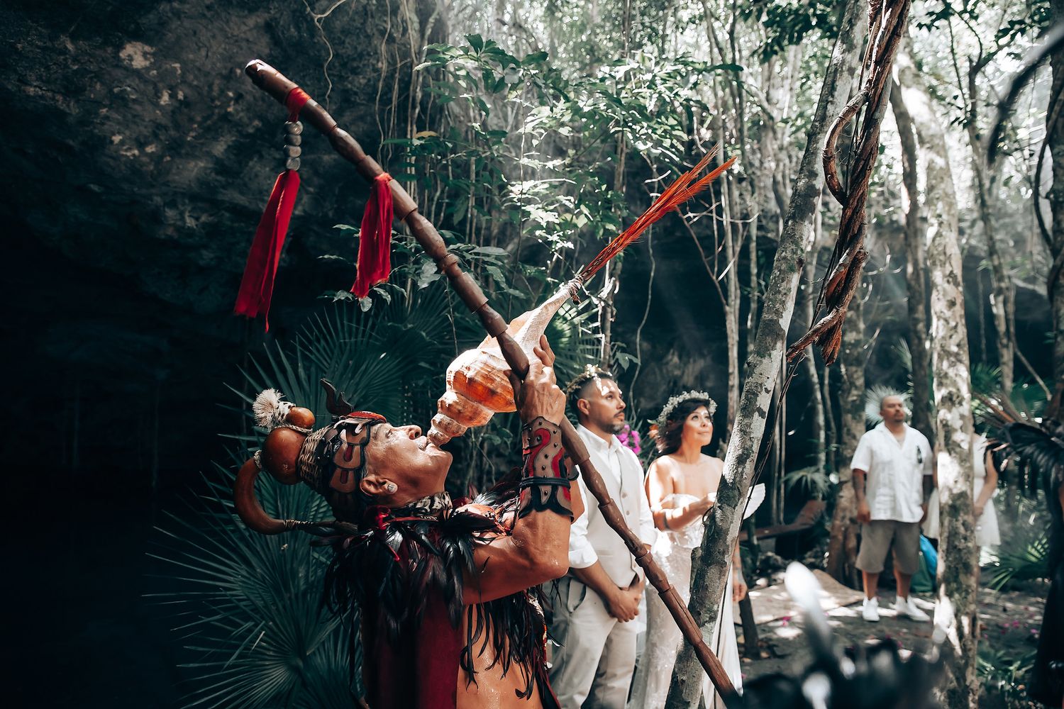 A group celebrates in a tropical forest setting with colorful decorations and natural light.