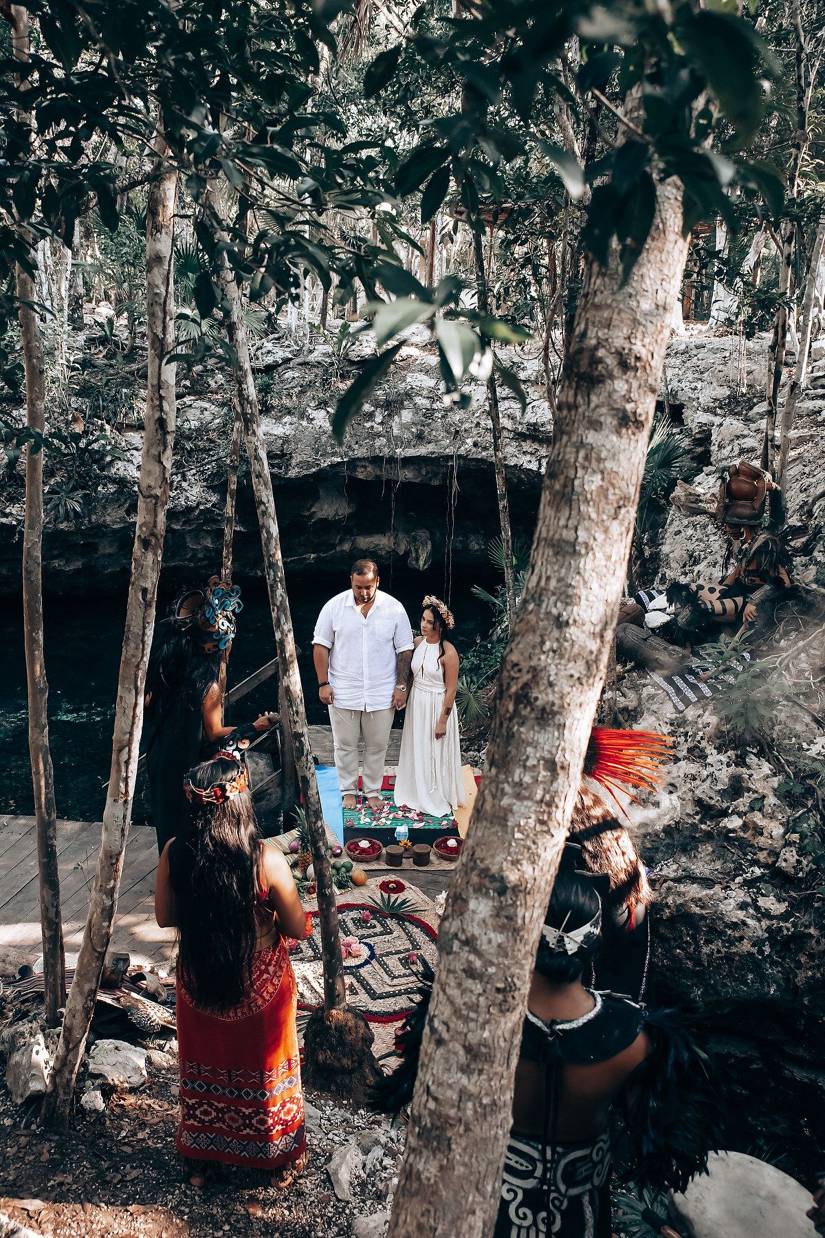 Traditional Mayan ceremony setup in a natural cave setting with decorative rugs and ritual items.