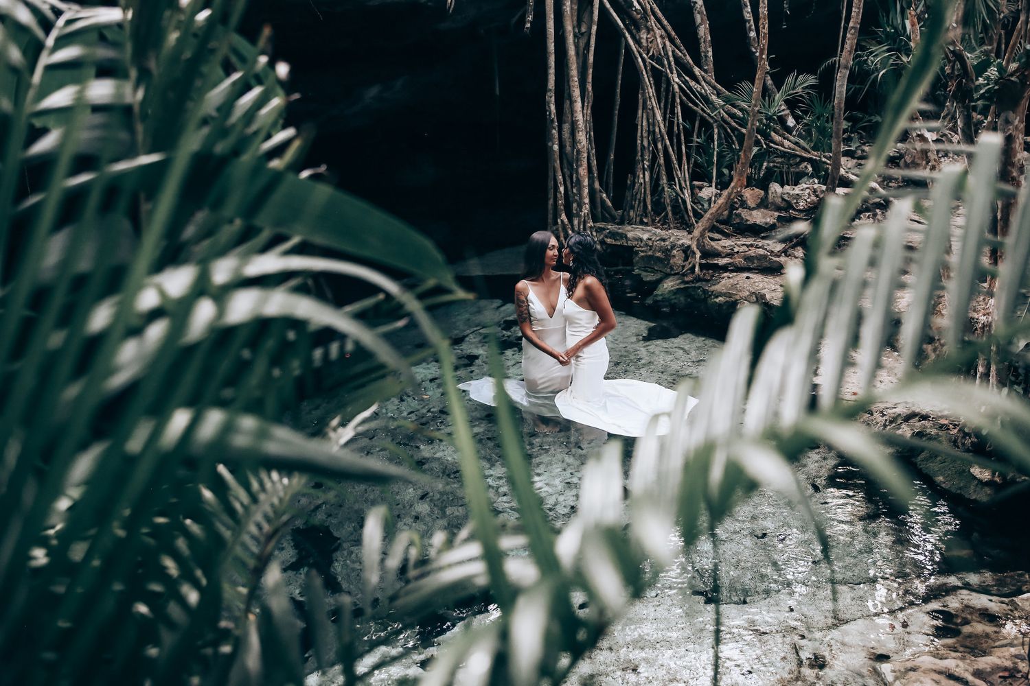 Tropical garden wedding scene with palm leaves in the foreground.