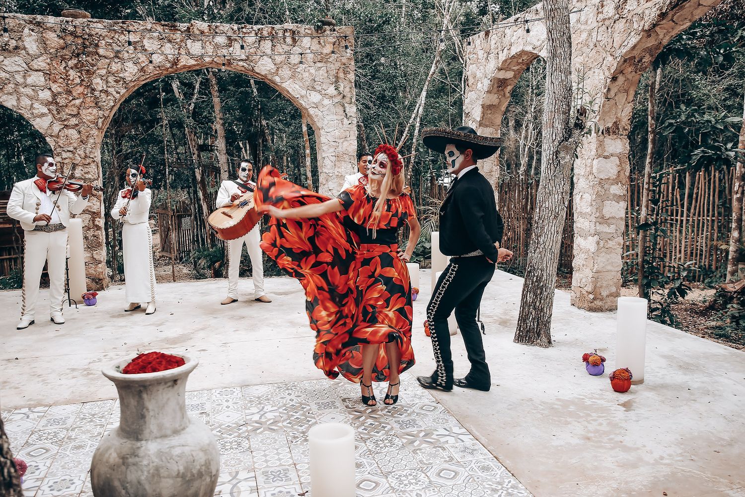 Outdoor wedding celebration with red dress and gothic decorations along stone pathway.