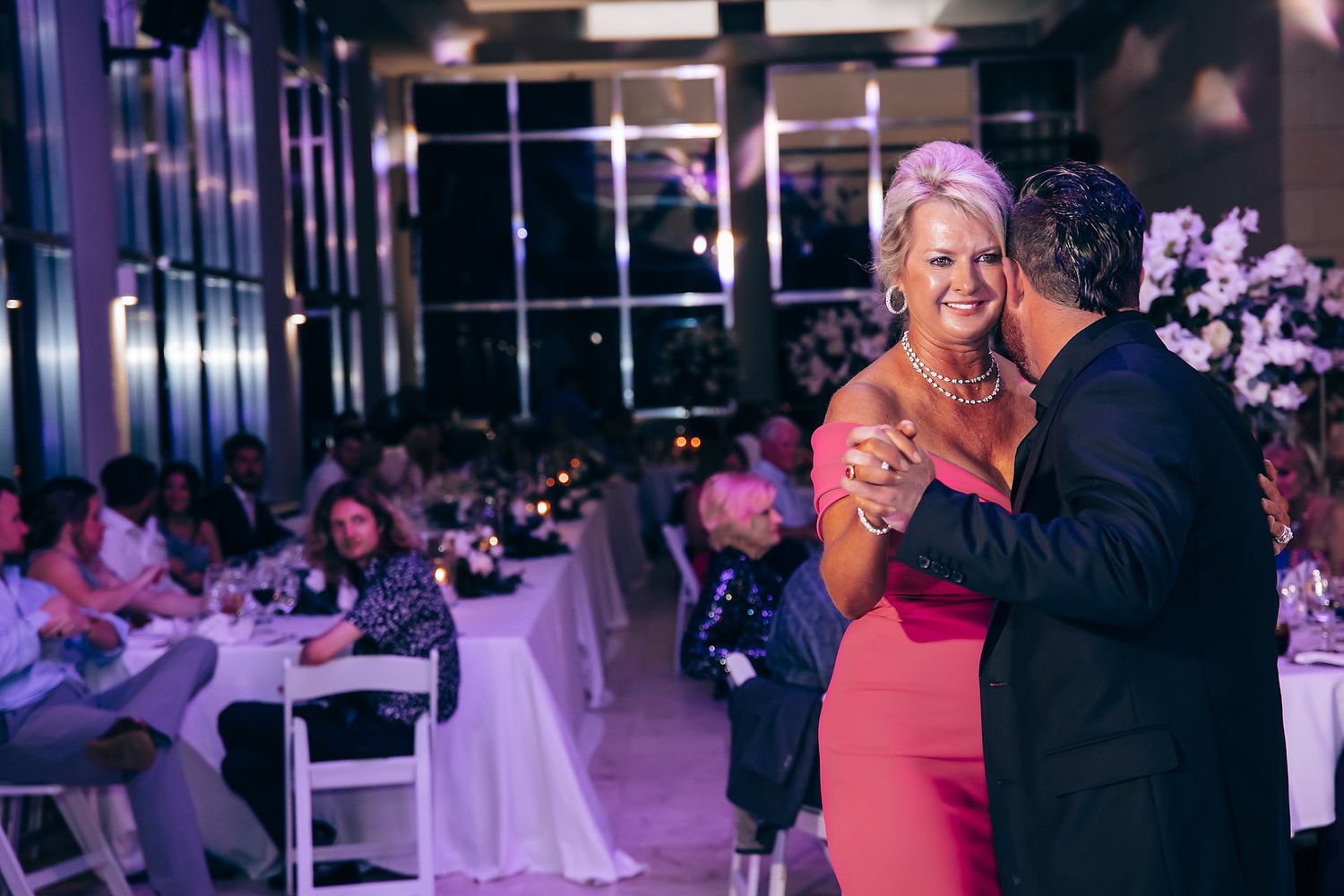 Couple shares an intimate dance moment under purple lighting at their wedding reception.