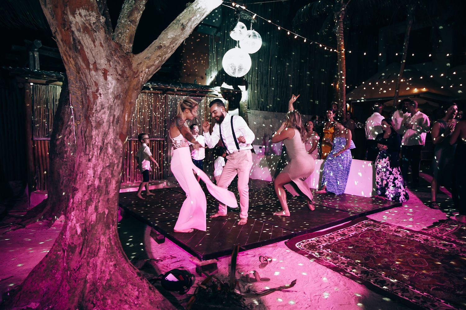 Evening wedding reception with string lights creating a magical atmosphere under palm trees.