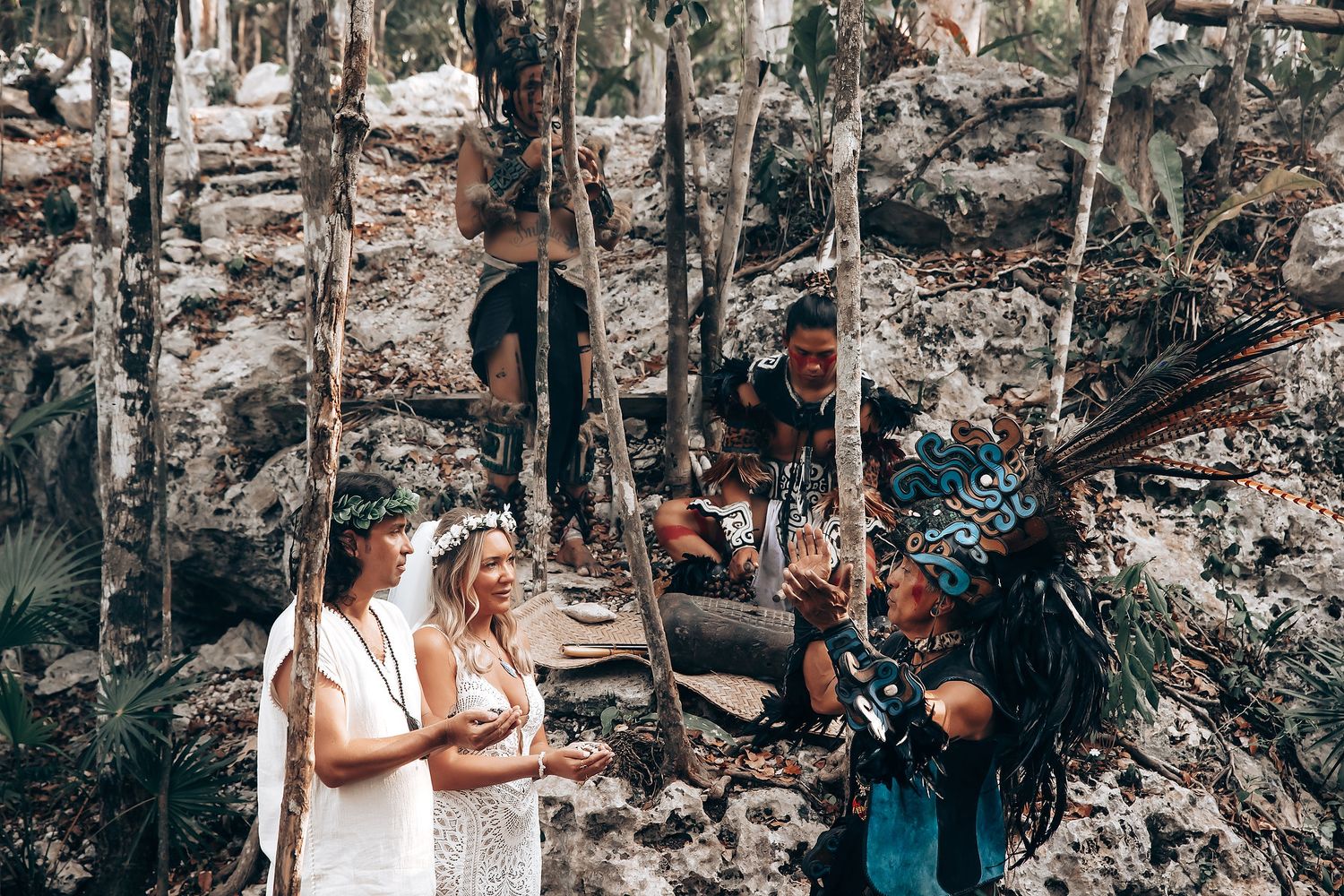 Wedding couple embracing in a rustic outdoor setting surrounded by stone walls and natural greenery.