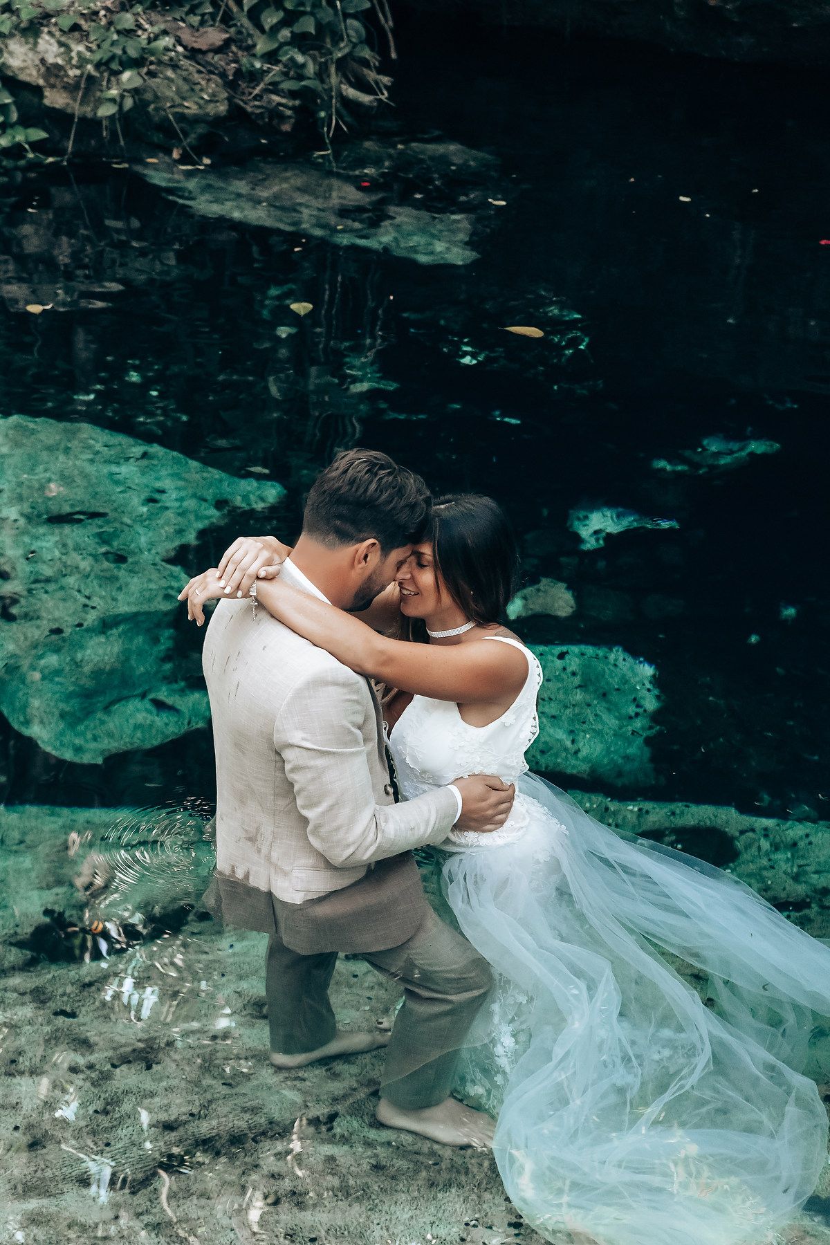 Intimate wedding photo session at the edge of a crystal clear cenote in Mexico.