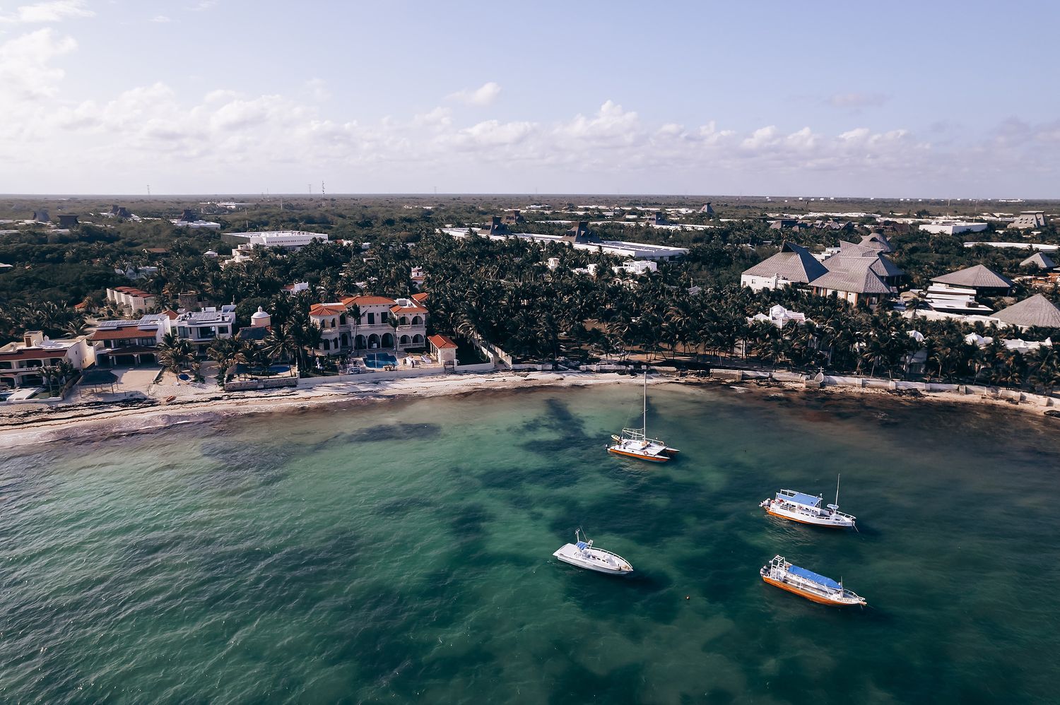 Aerial view of coastal venue with boats anchored in turquoise waters.
