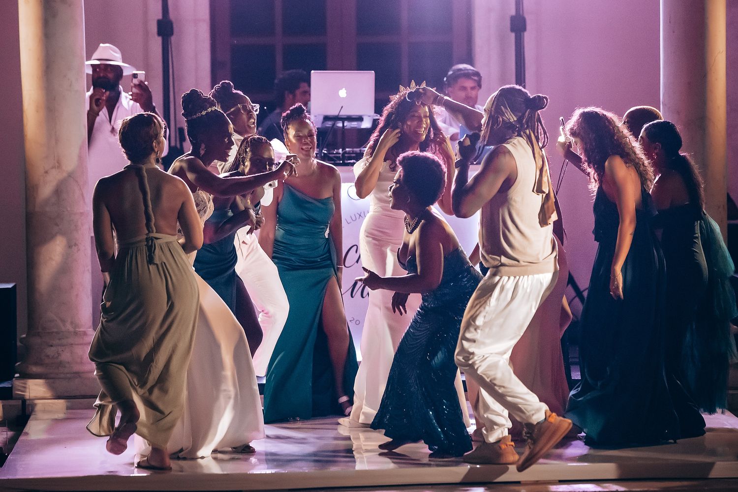 Wedding reception dance floor filled with guests in elegant evening lighting.