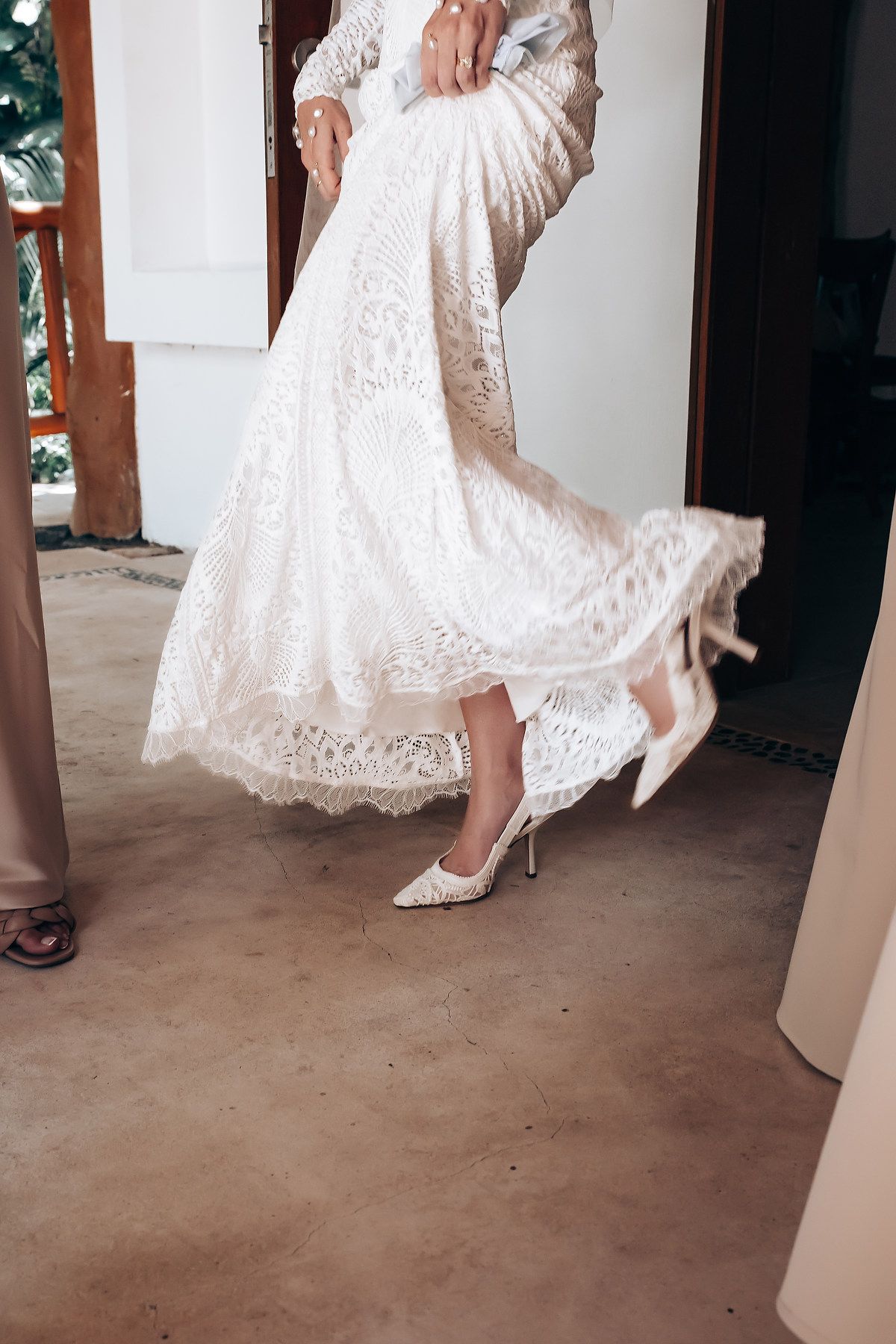 Close-up details of white lace wedding dress and shoes in motion.