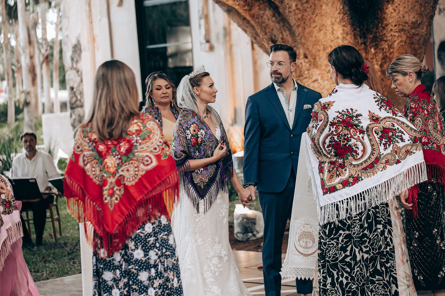 A group of wedding guests dance and celebrate together during an outdoor reception celebration.