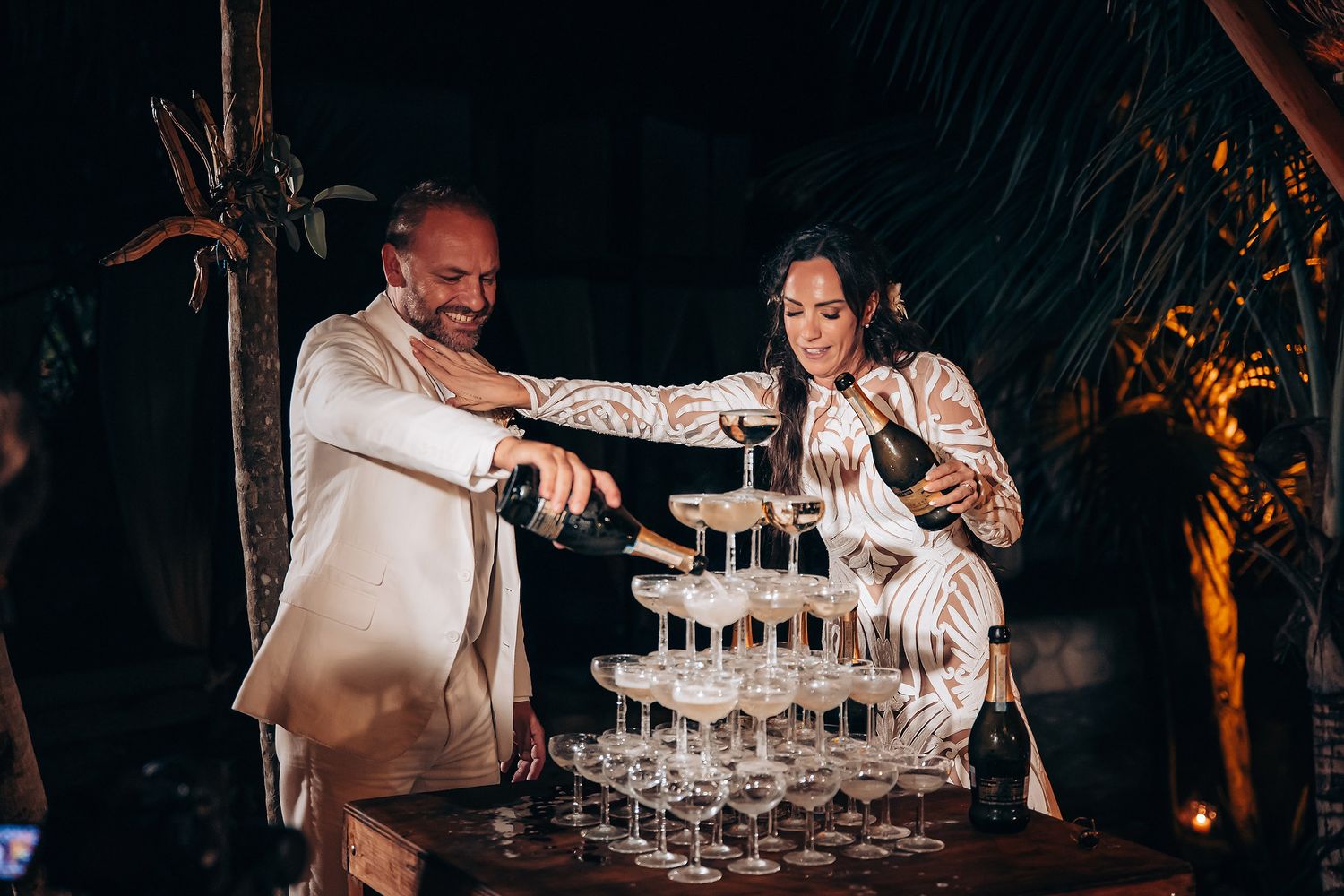 Wedding celebration with champagne tower being filled at an elegant evening reception.