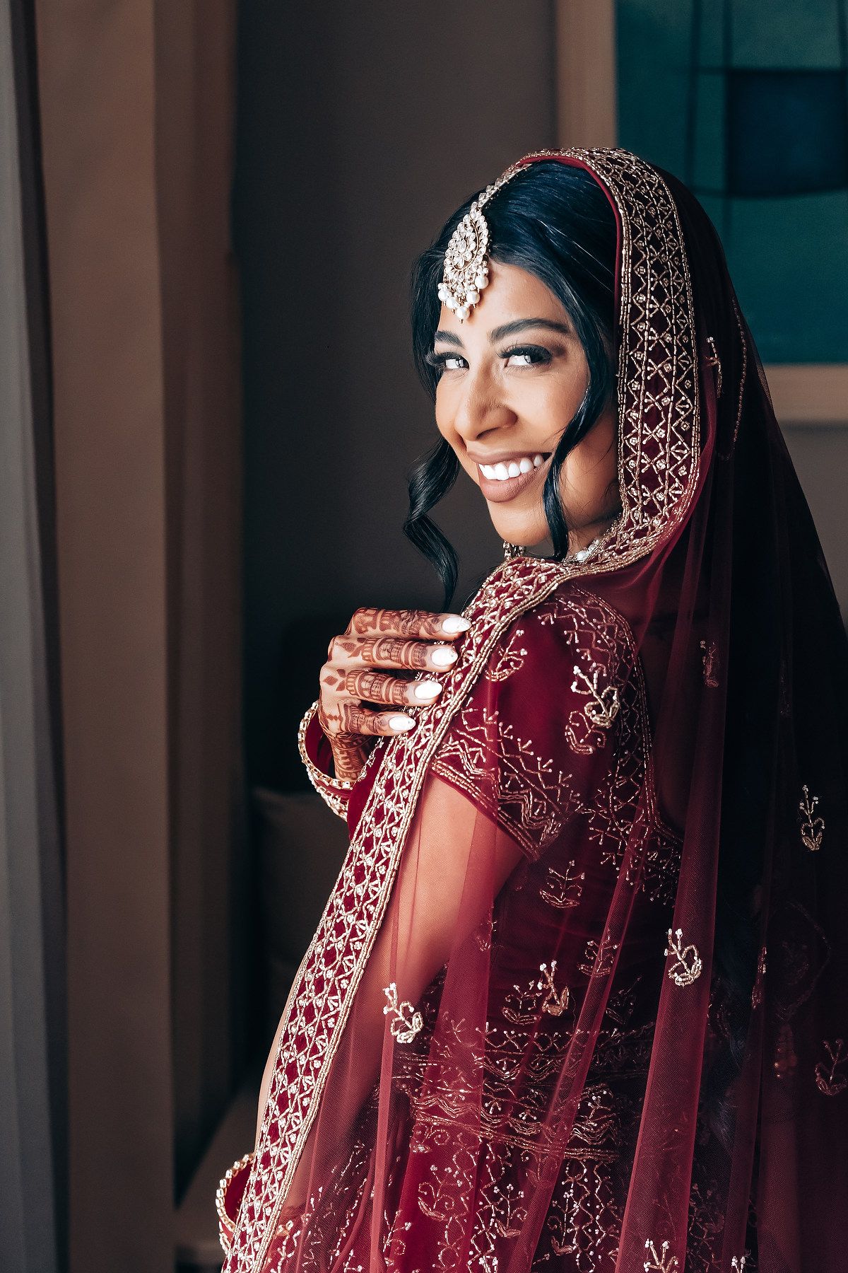 Traditional Indian bride wearing deep red lehenga with embellished border and jewelry.