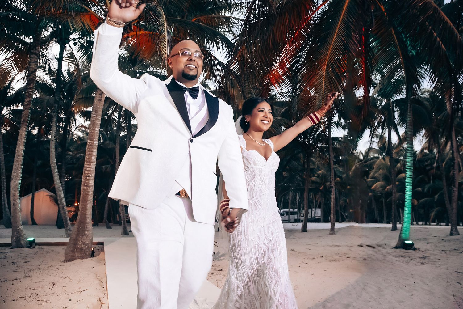 Joyful celebration on a tropical beach with palm trees at sunset.