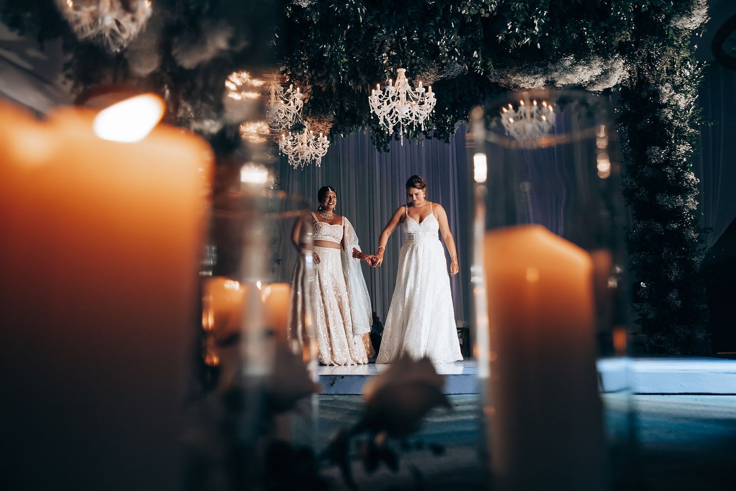 Candlelit wedding ceremony space with soft lighting and elegant white drapery in the background.