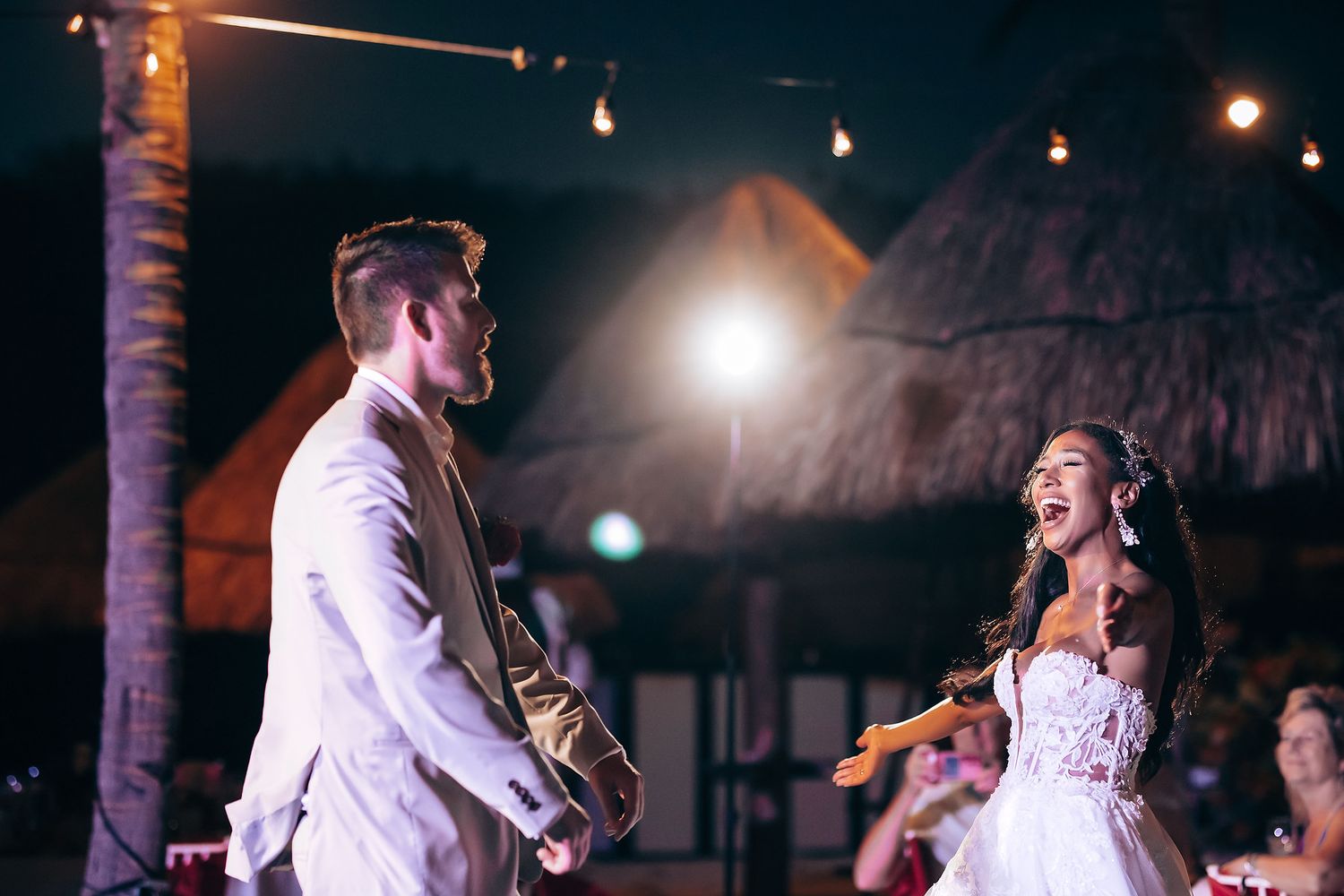Romantic dance under string lights at an outdoor evening reception.