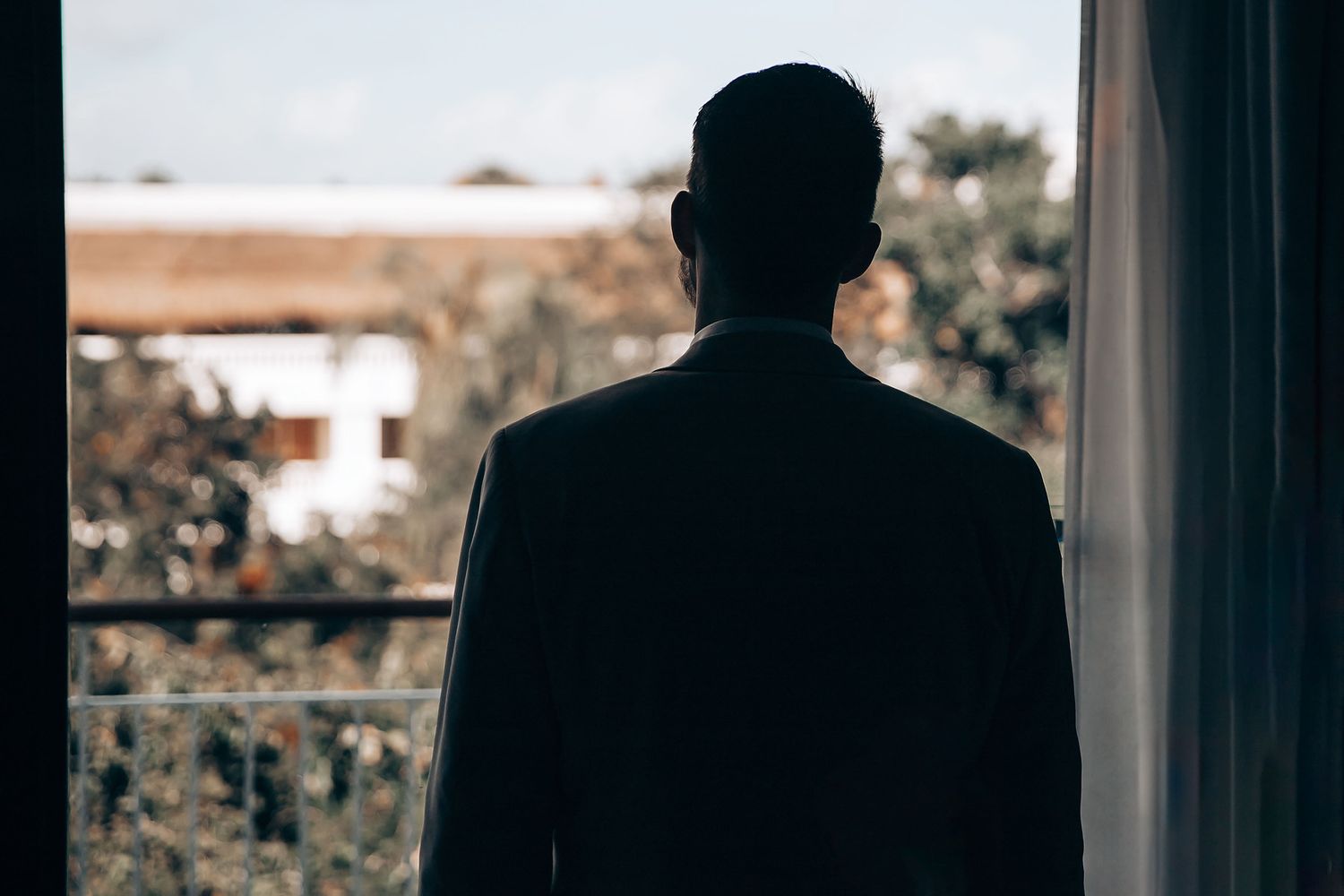 Silhouettes of wedding party members standing in a bright window.