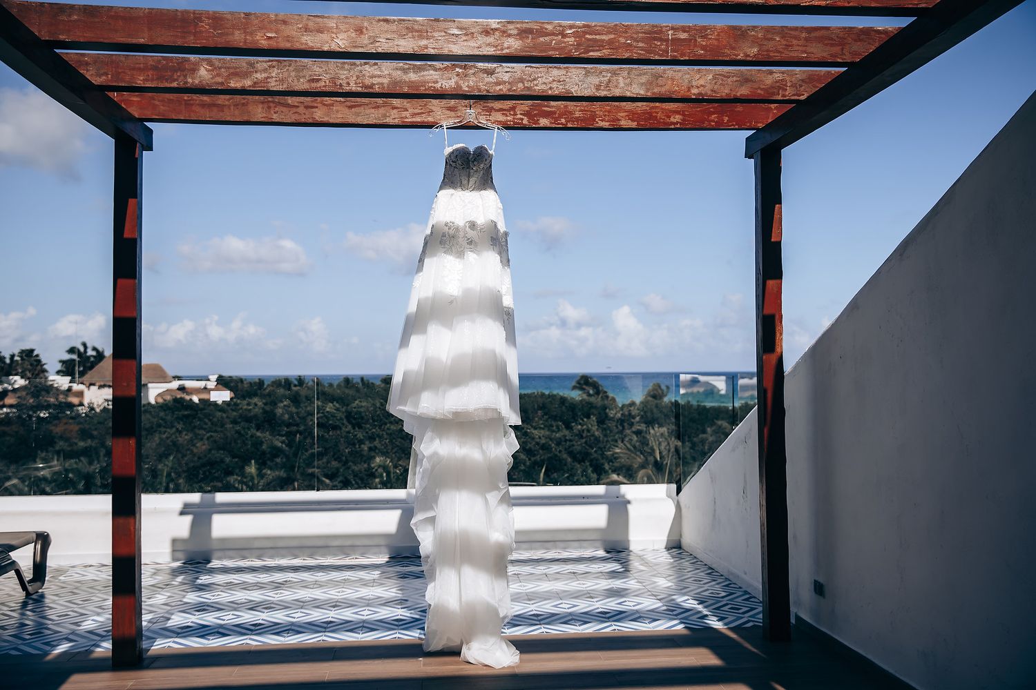 Beachfront wedding venue with white columns and wooden beams against a bright blue sky.