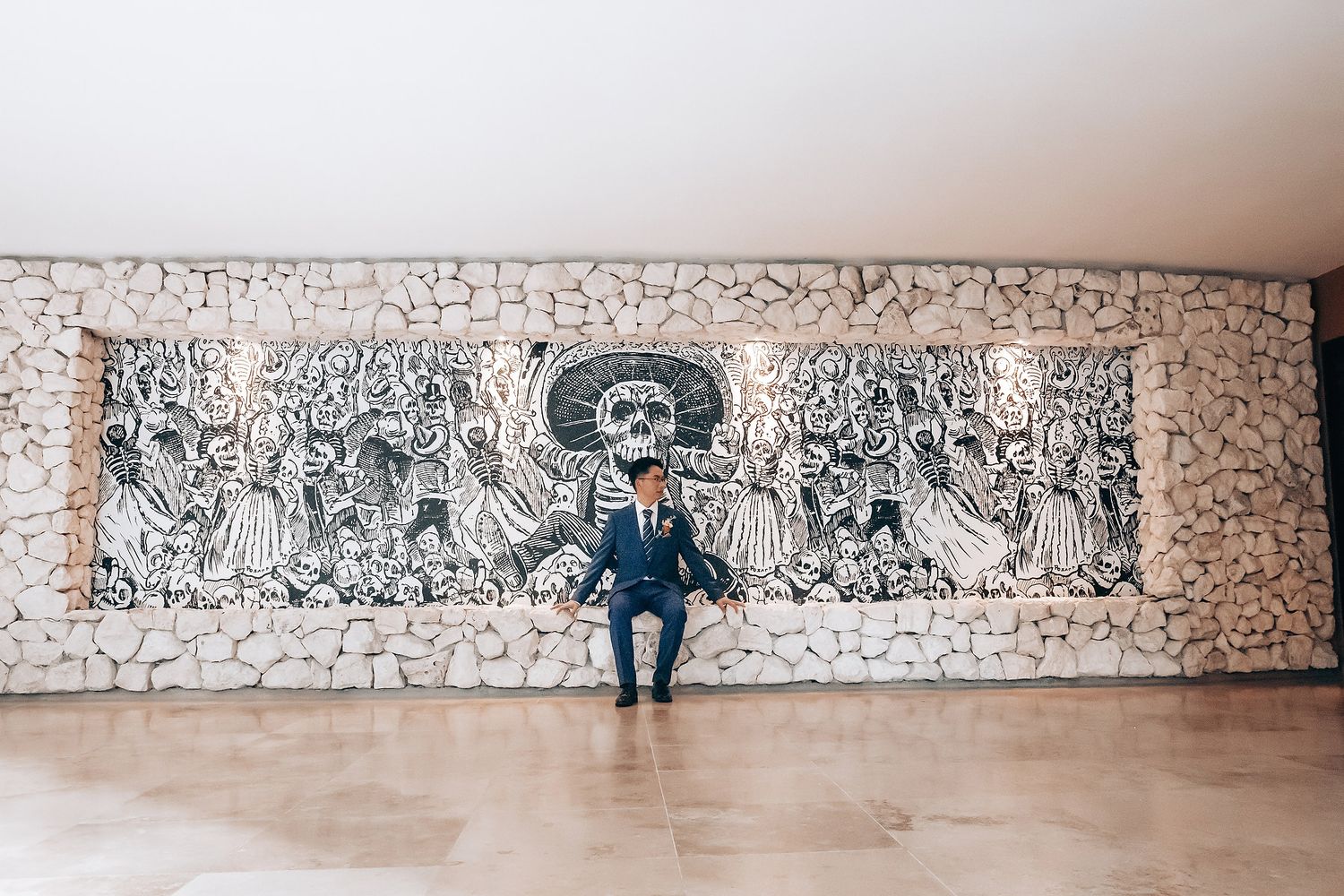 Person sitting alone on bench against long wall with artistic graffiti murals.