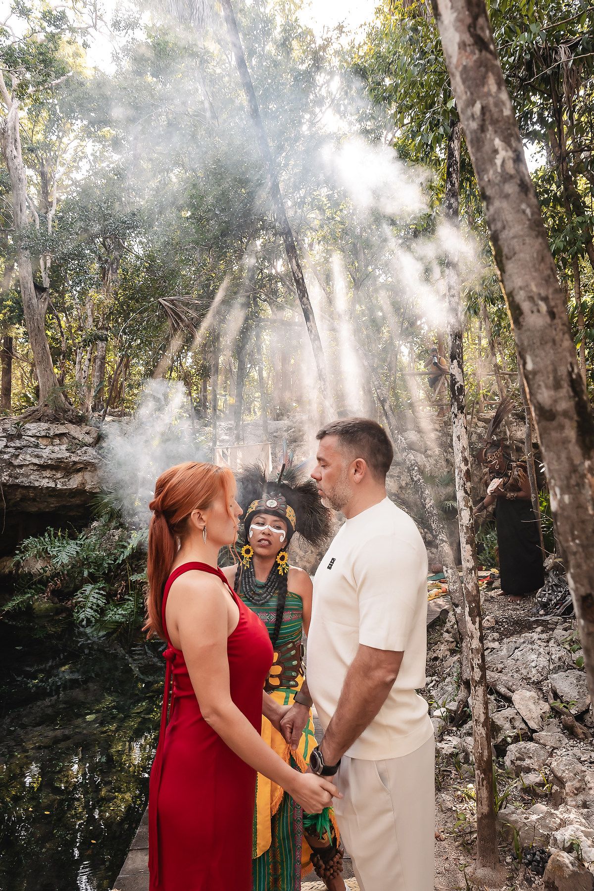 Sunbeams filter through trees during a spiritual ceremony in a cenote cave.