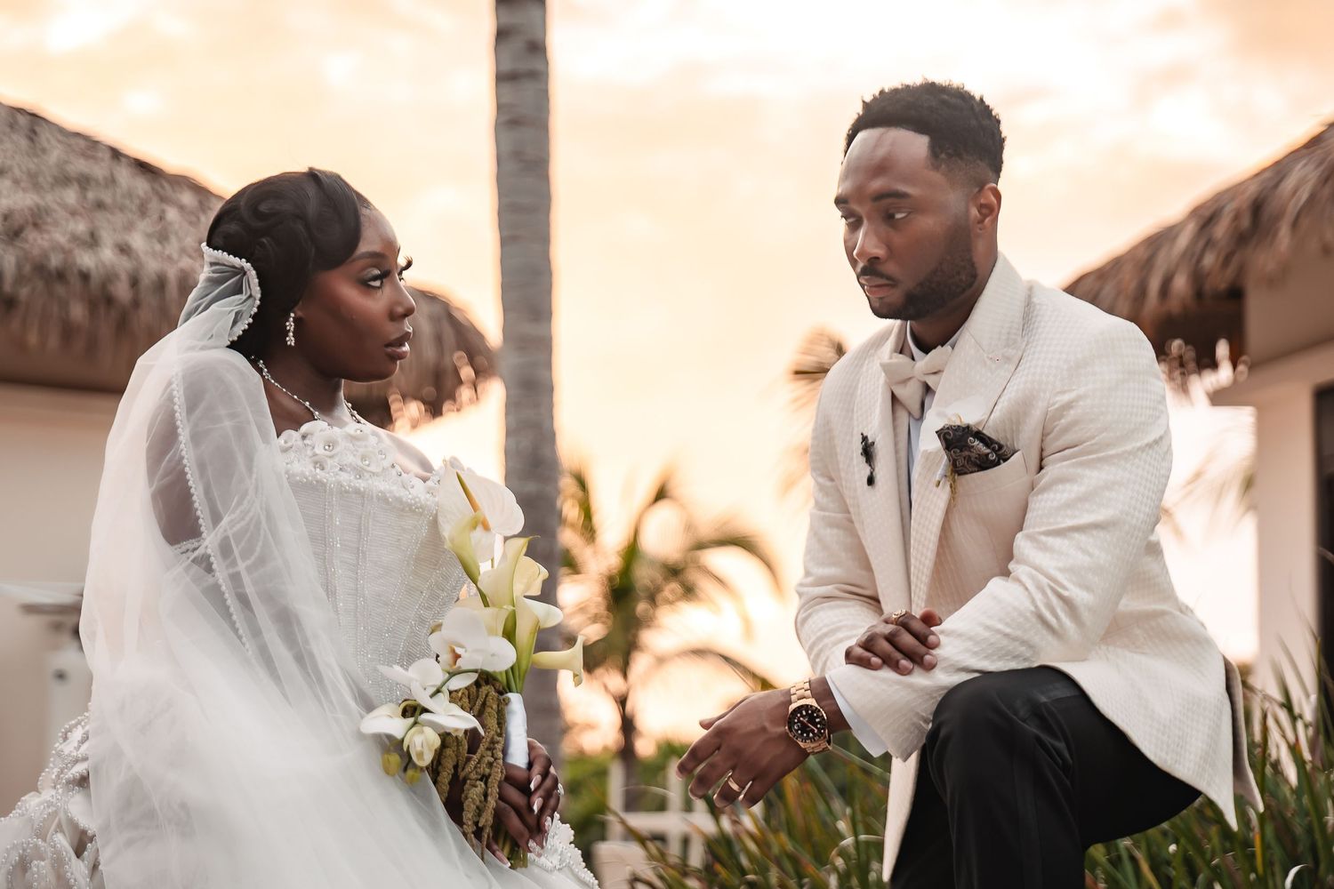 A romantic sunset wedding moment captured at a tropical beach resort with palm trees in the background.