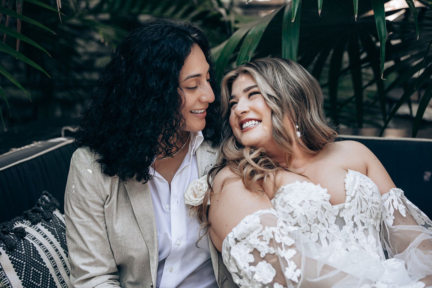 Tender moment between newlyweds captured in natural outdoor setting with lush greenery.