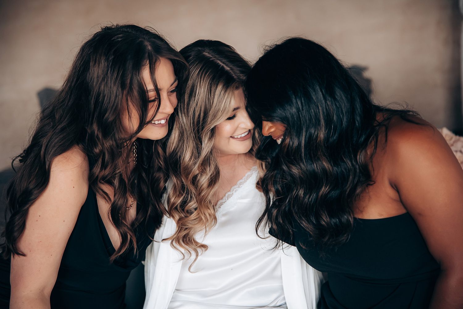 Group hugging and smiling in white outfits during intimate gathering.