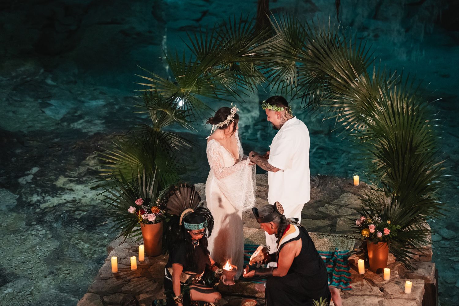 Candlelit cave dinner features couple dining at low table with tropical decorations.