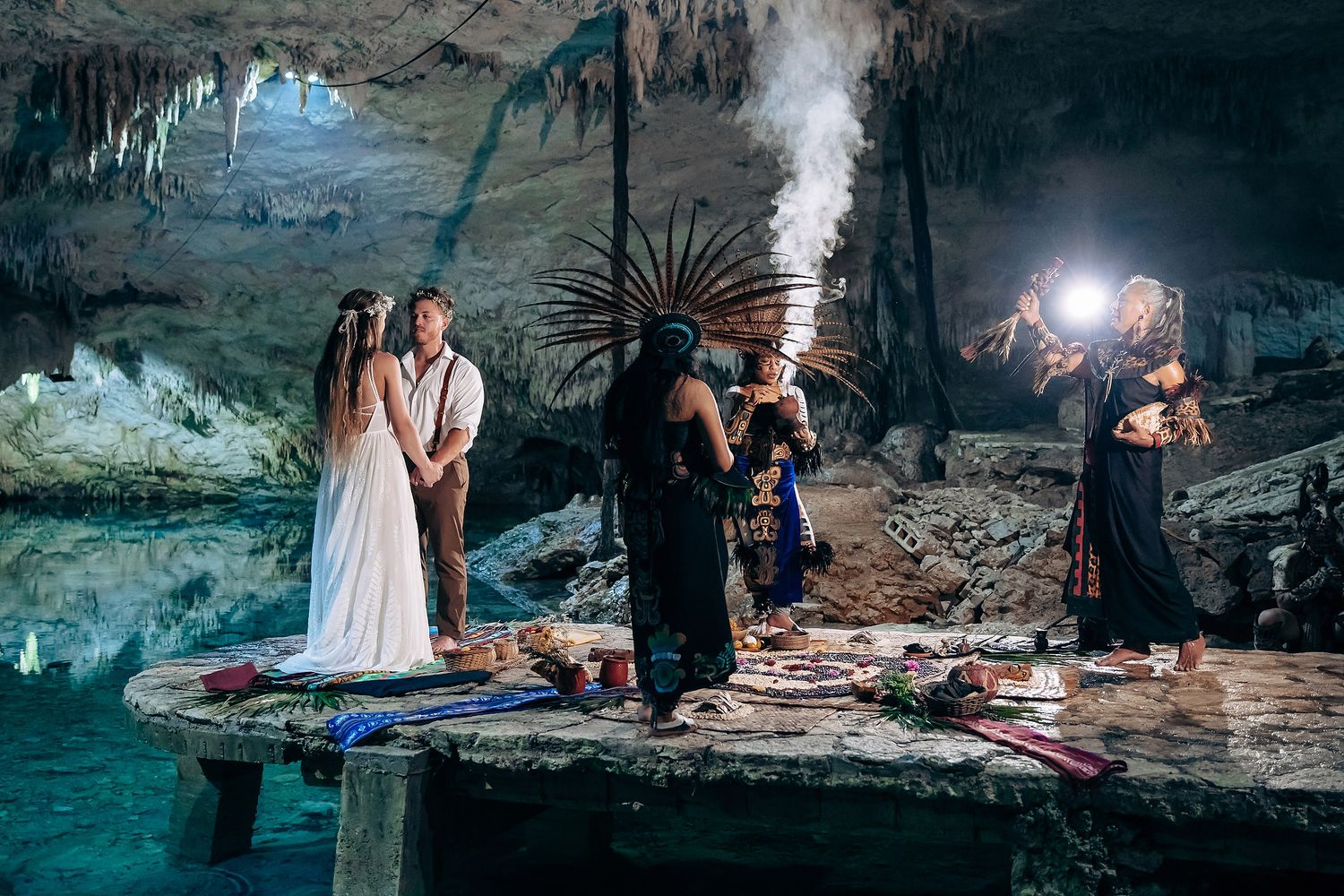 Dramatic cave wedding photoshoot with moody lighting and ethereal mist over turquoise waters.