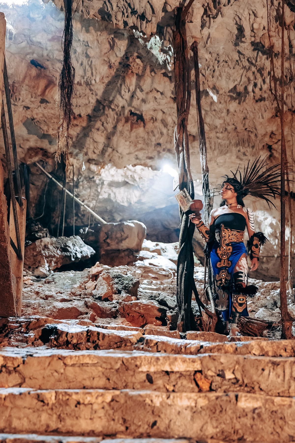 Wedding ceremony taking place in a scenic cave setting with turquoise water and natural rock formations.