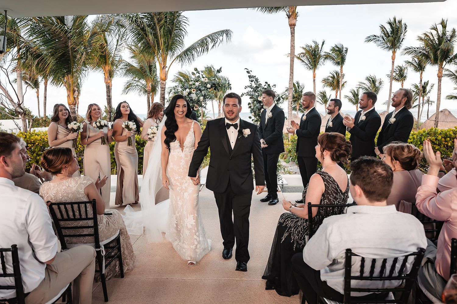 Wedding reception celebration with guests in formal attire gathered under an outdoor venue.