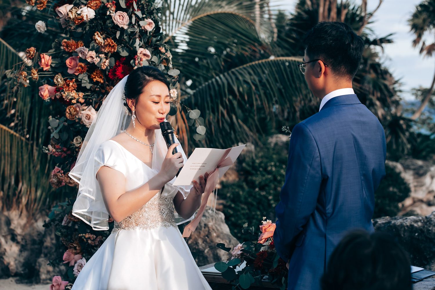 Outdoor wedding ceremony with floral arch and guests in attendance.