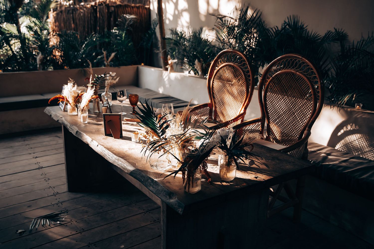 Romantic wedding reception table setting with candles and boho decor at dusk.