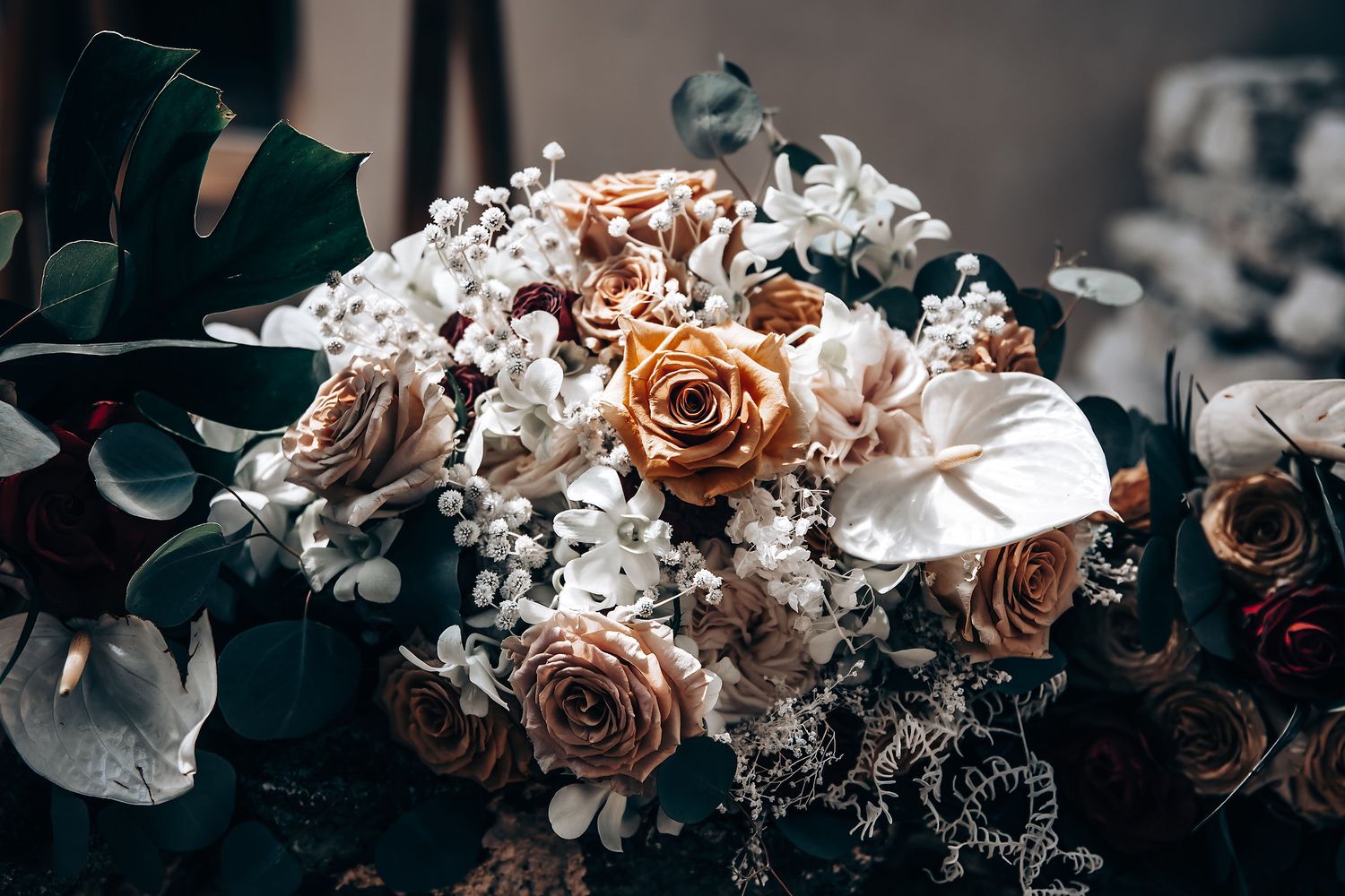 Elegant wedding bouquet with peach roses and white flowers against dark background.