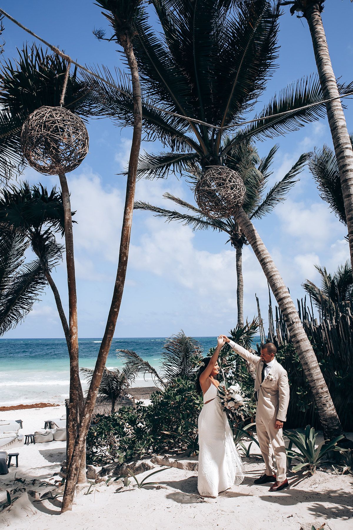 Palm trees sway on a tropical beach with white sand and crystal clear blue ocean waters.