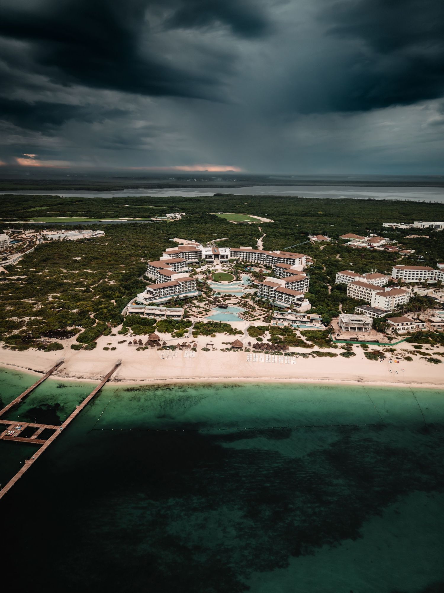 Dramatic aerial view of coastal resort property against dark stormy sky.