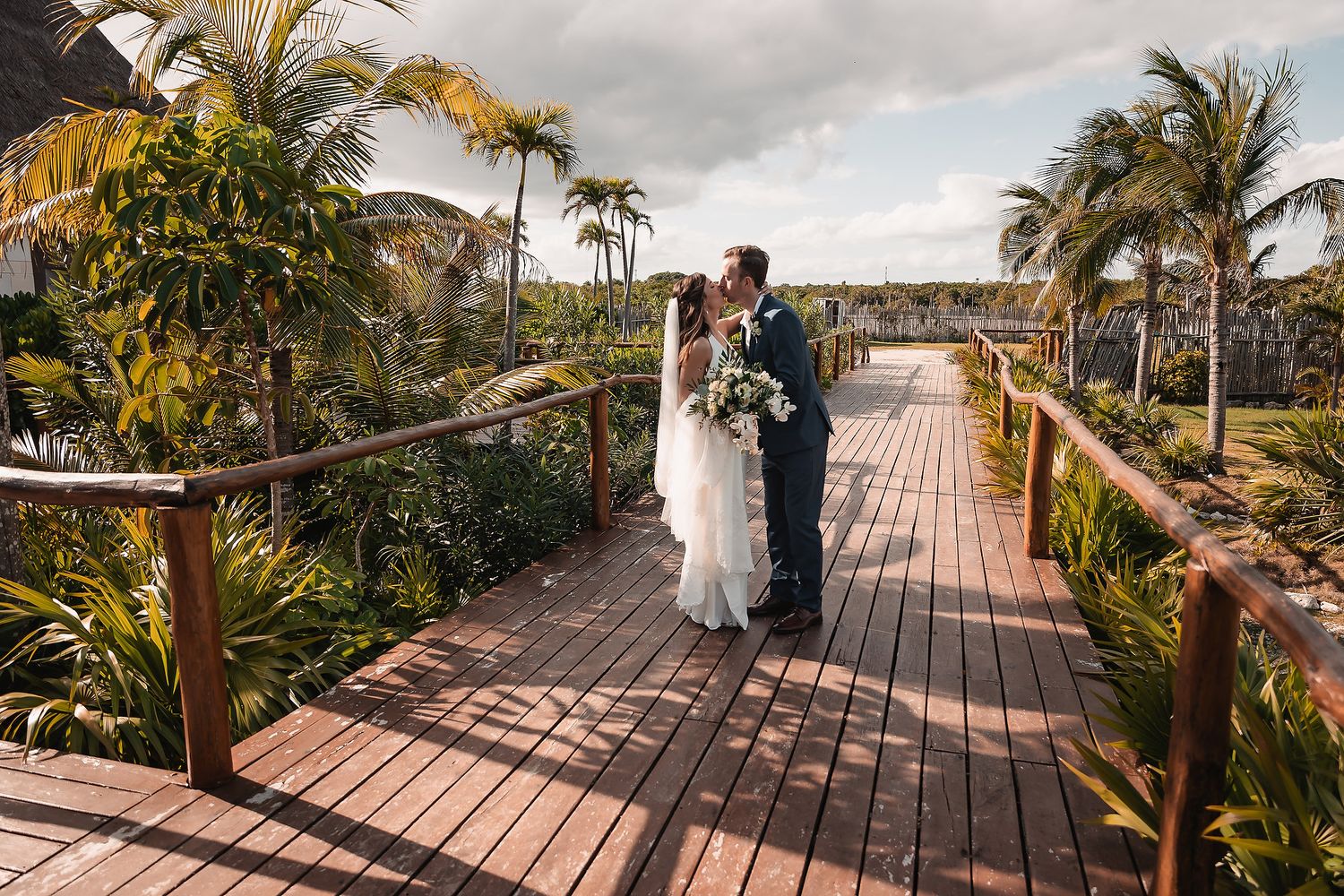 Tropical palm-lined wooden boardwalk leading to a beach destination.