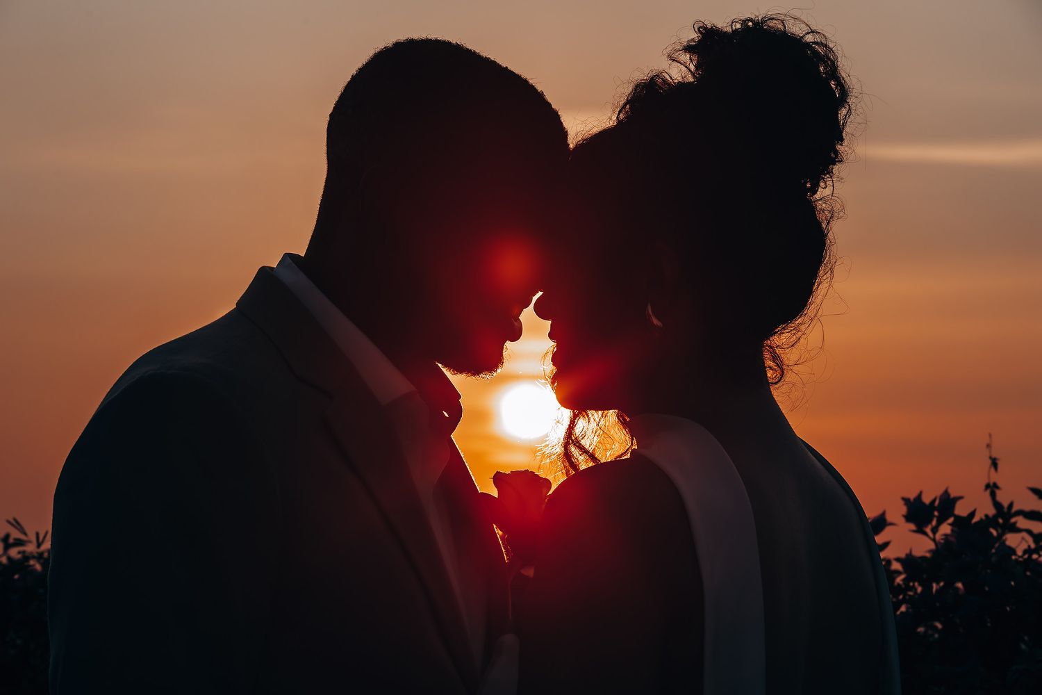 Romantic sunset silhouettes captured during golden hour at outdoor celebration.