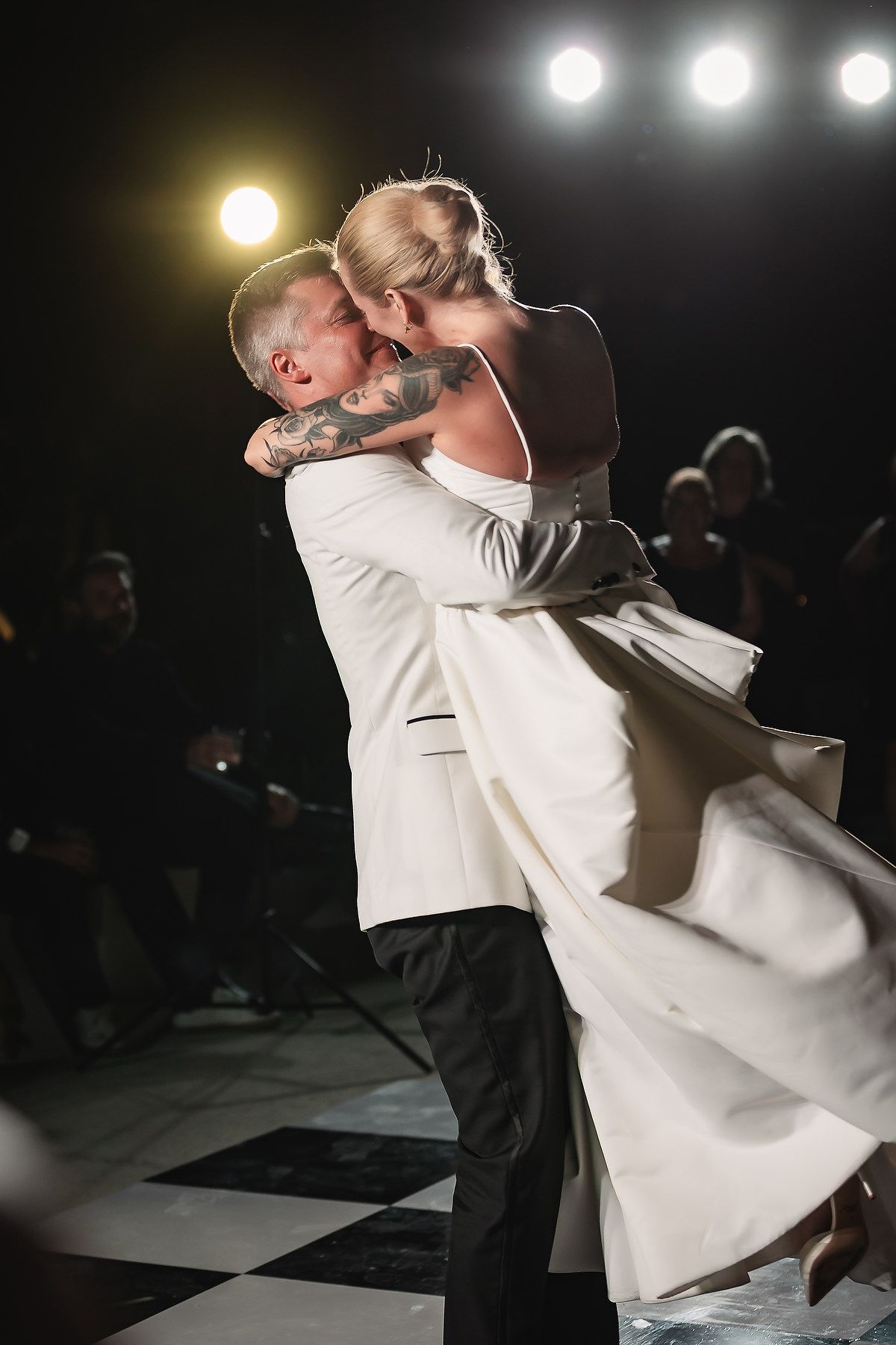 Dramatic dance floor moment captured during wedding reception with spotlighting.