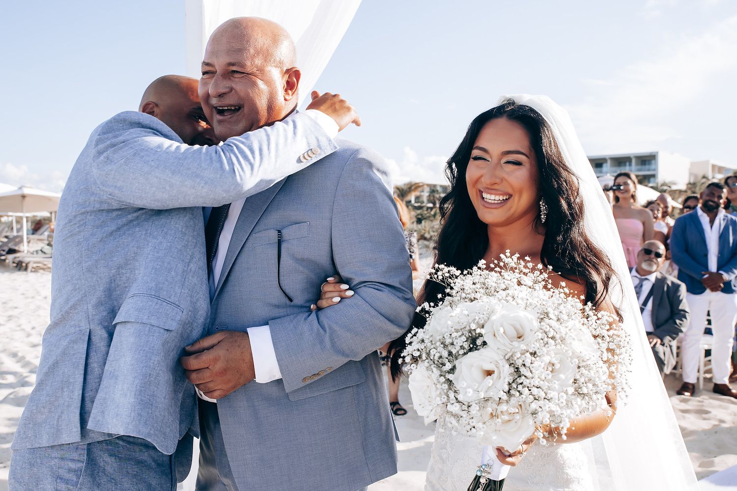 Wedding celebration moments on a sunny beach with joyful embraces and laughter.