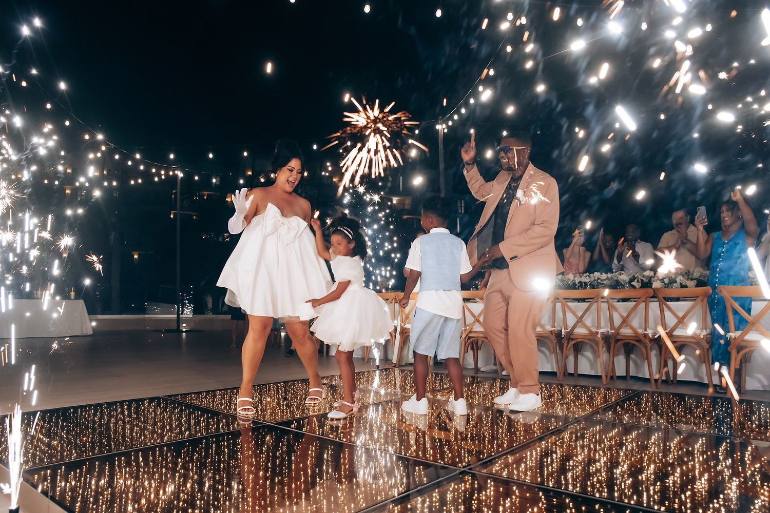 Sparklers and string lights create a magical atmosphere during an evening beach celebration.