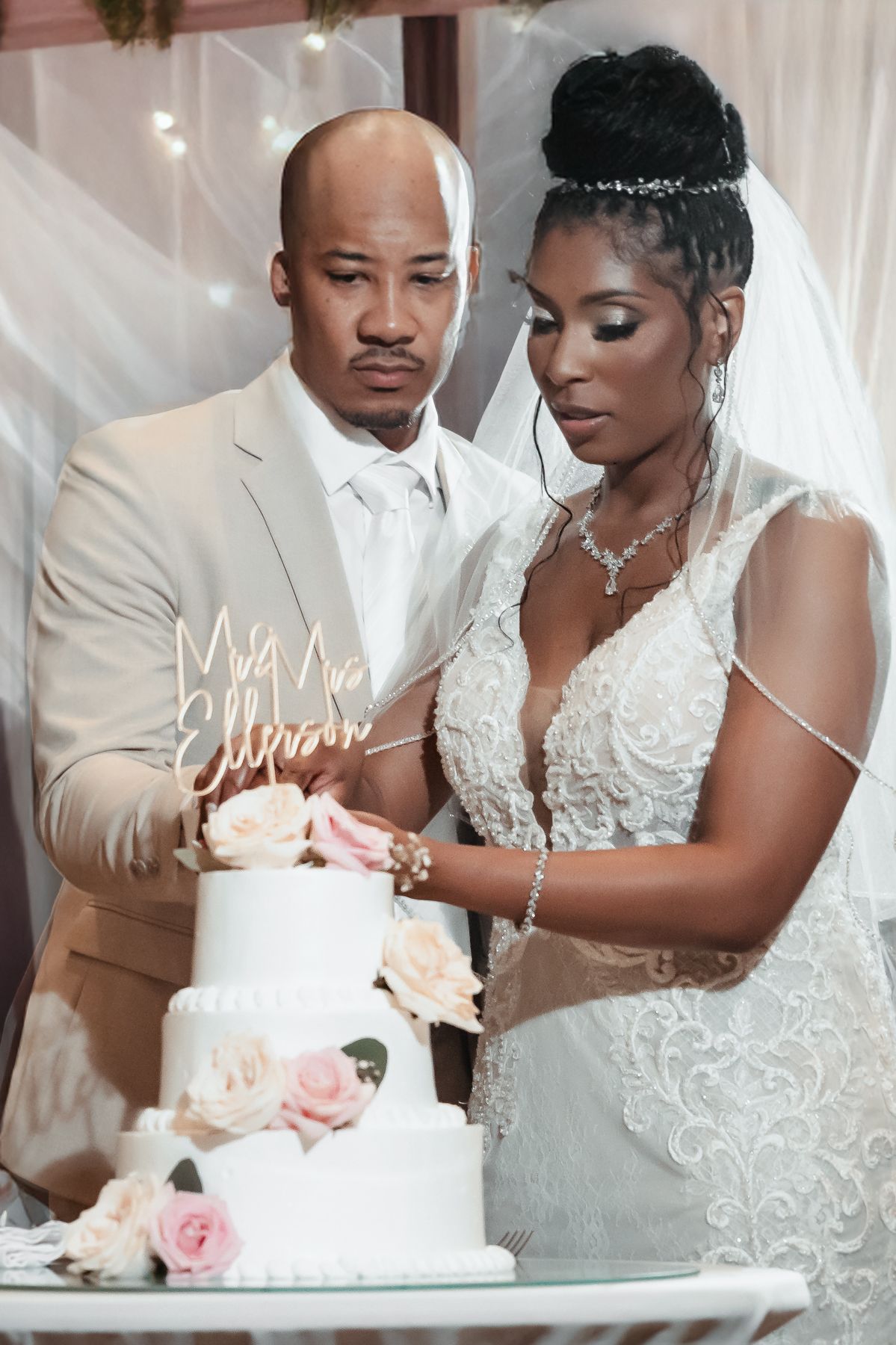 Bride and groom cutting their white wedding cake with floral decorations at their elegant wedding reception.