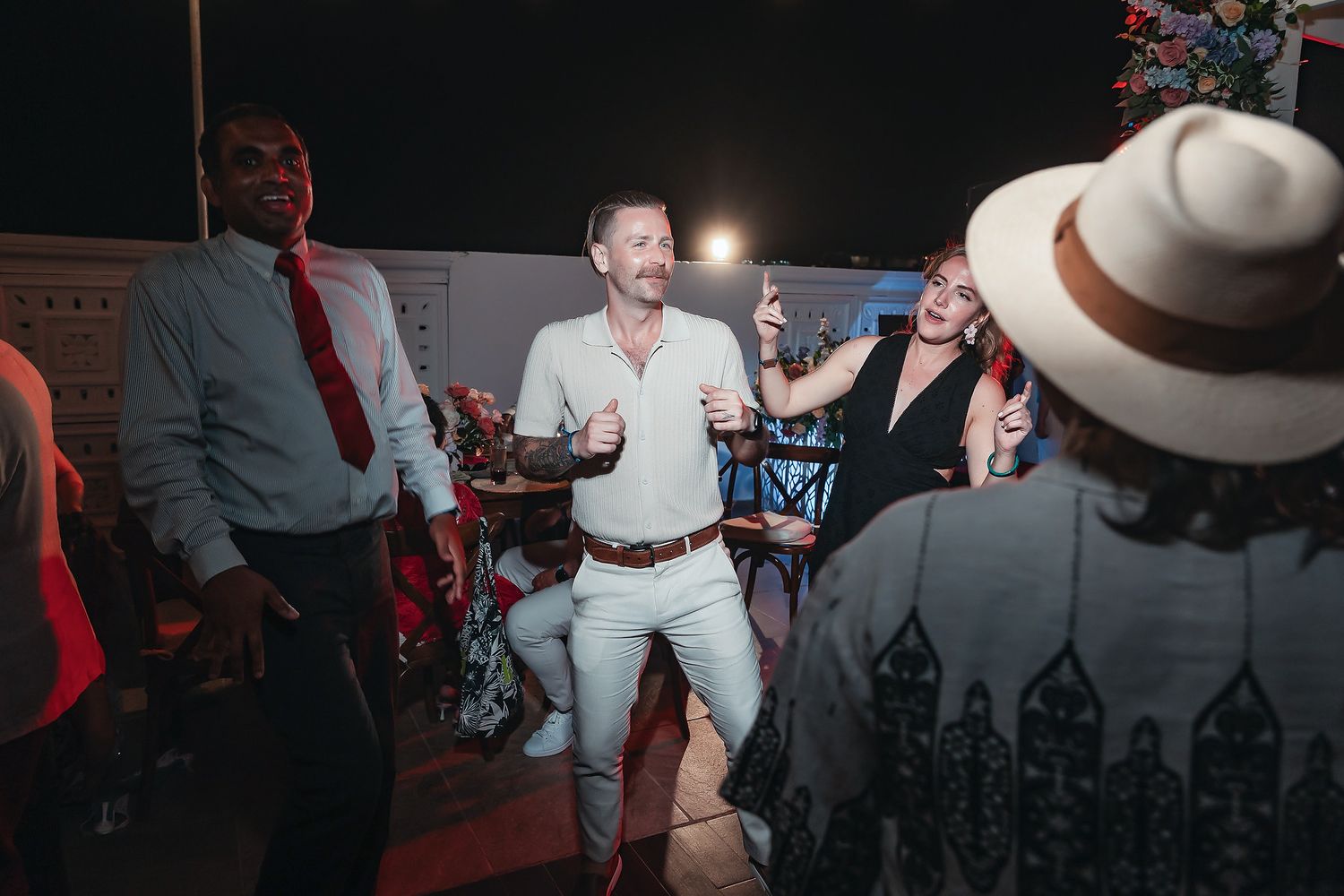 Group of adults dancing and celebrating outdoors at a festive nighttime party event.