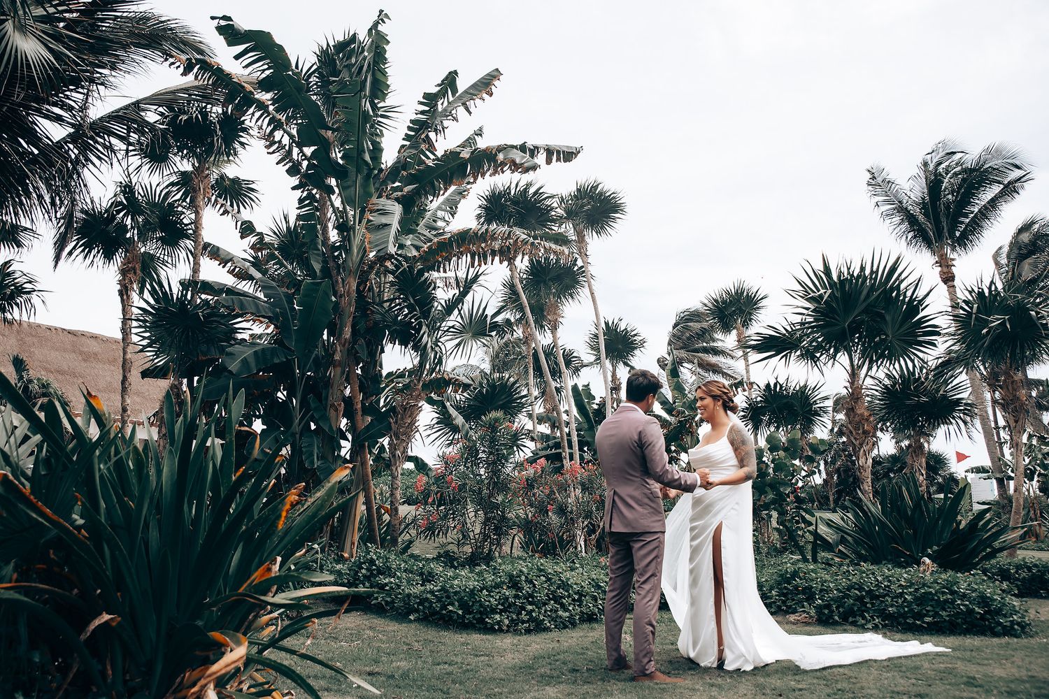 Wedding ceremony setup with palm trees and ocean backdrop at tropical beach location.