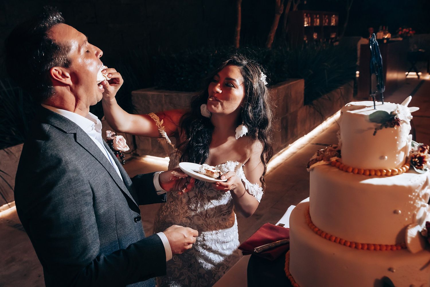 Newlyweds playfully share wedding cake during traditional cake cutting ceremony at reception.