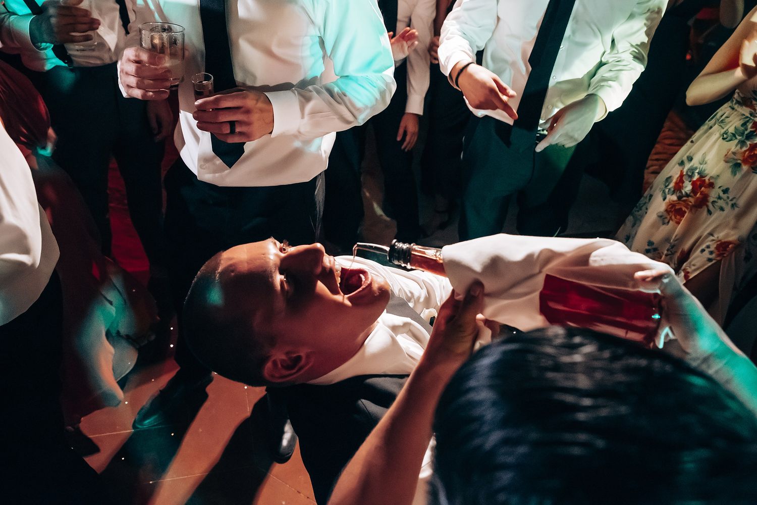 Guests dancing and celebrating at a wedding reception with colorful lighting effects.