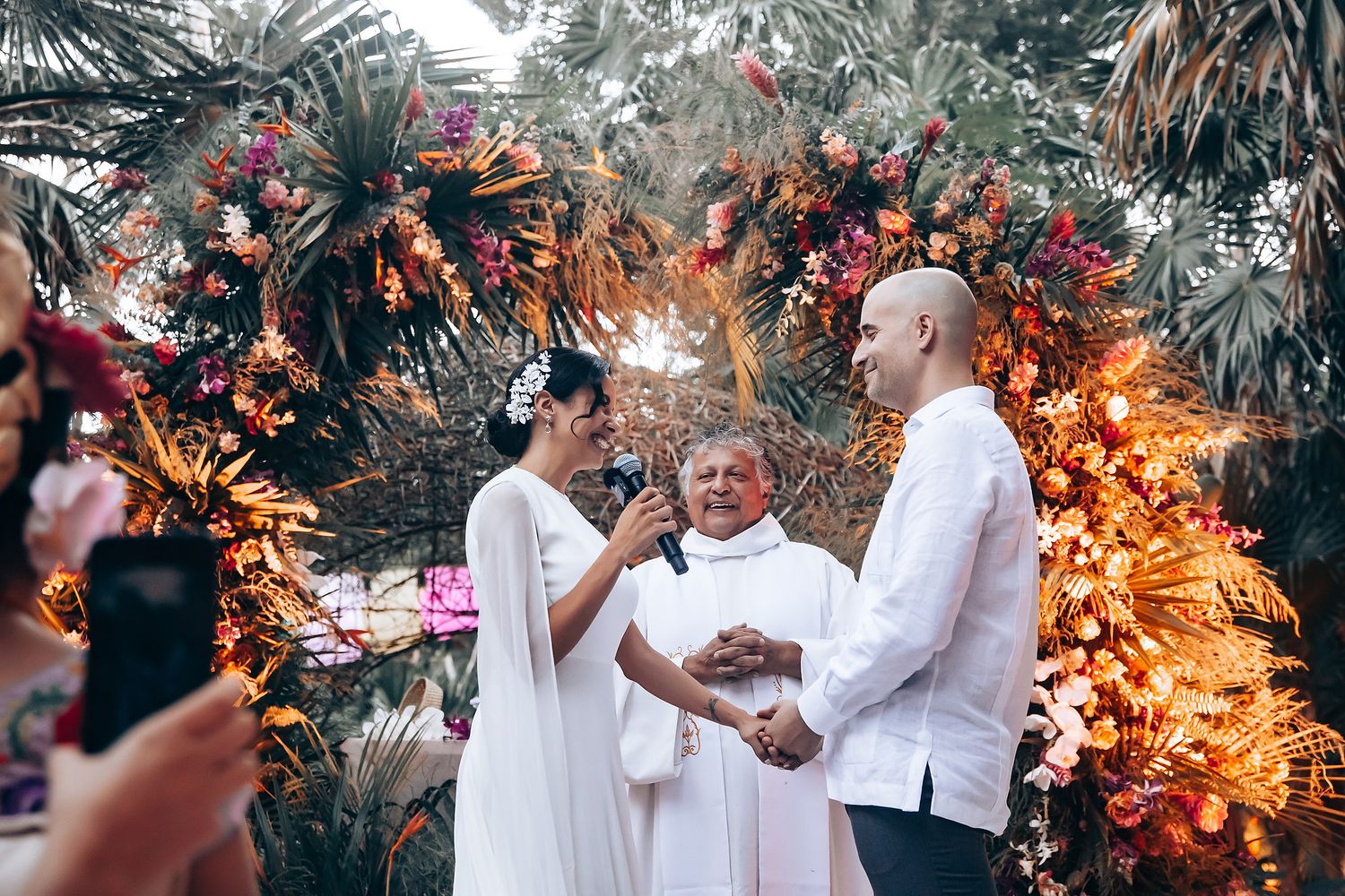 Wedding couple shares intimate moments in a tropical garden setting with palm trees and warm lighting.