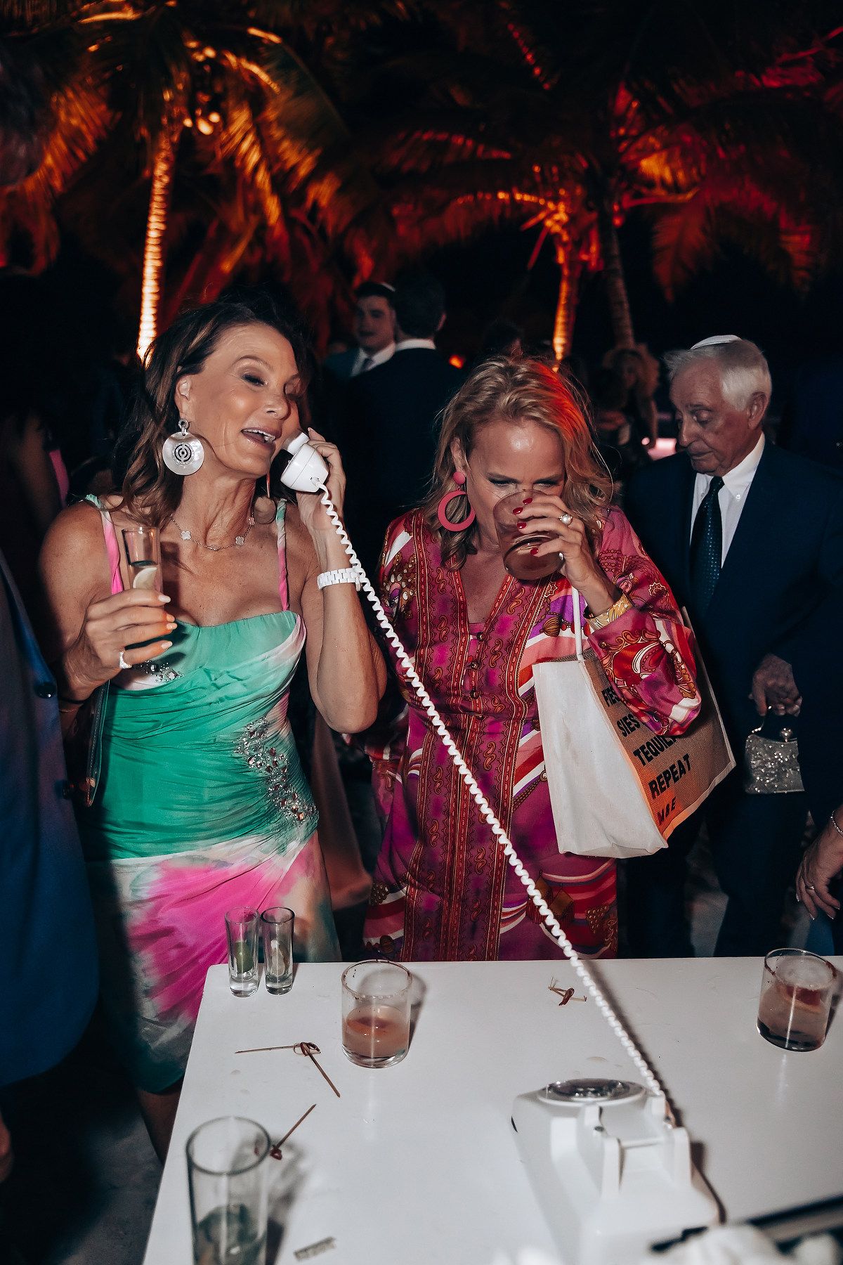 Wedding reception guests enjoying phone conversations at dining tables.
