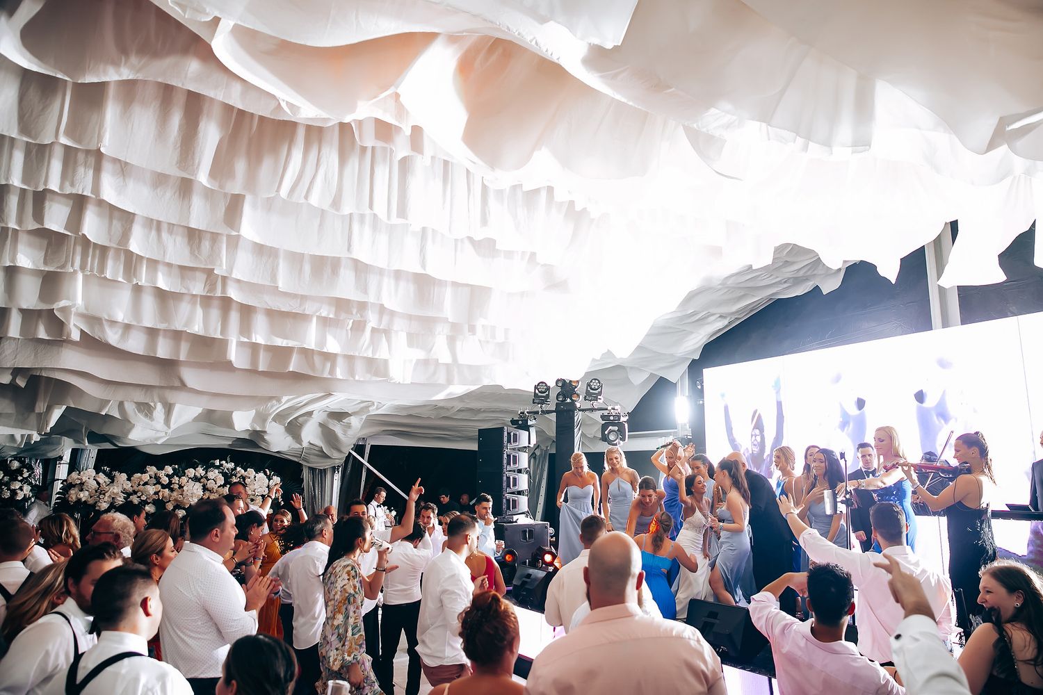 Wedding reception venue decorated with flowing white fabric ceiling installations.