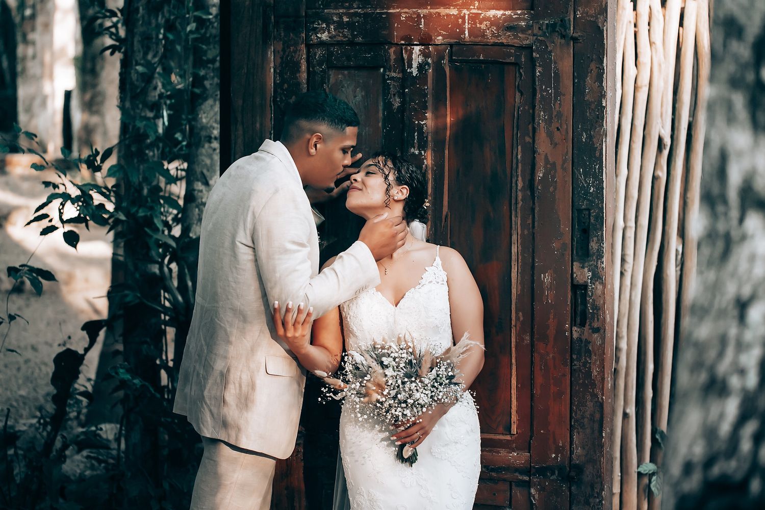 An intimate wedding moment captured against rustic wooden doors in a forest setting.