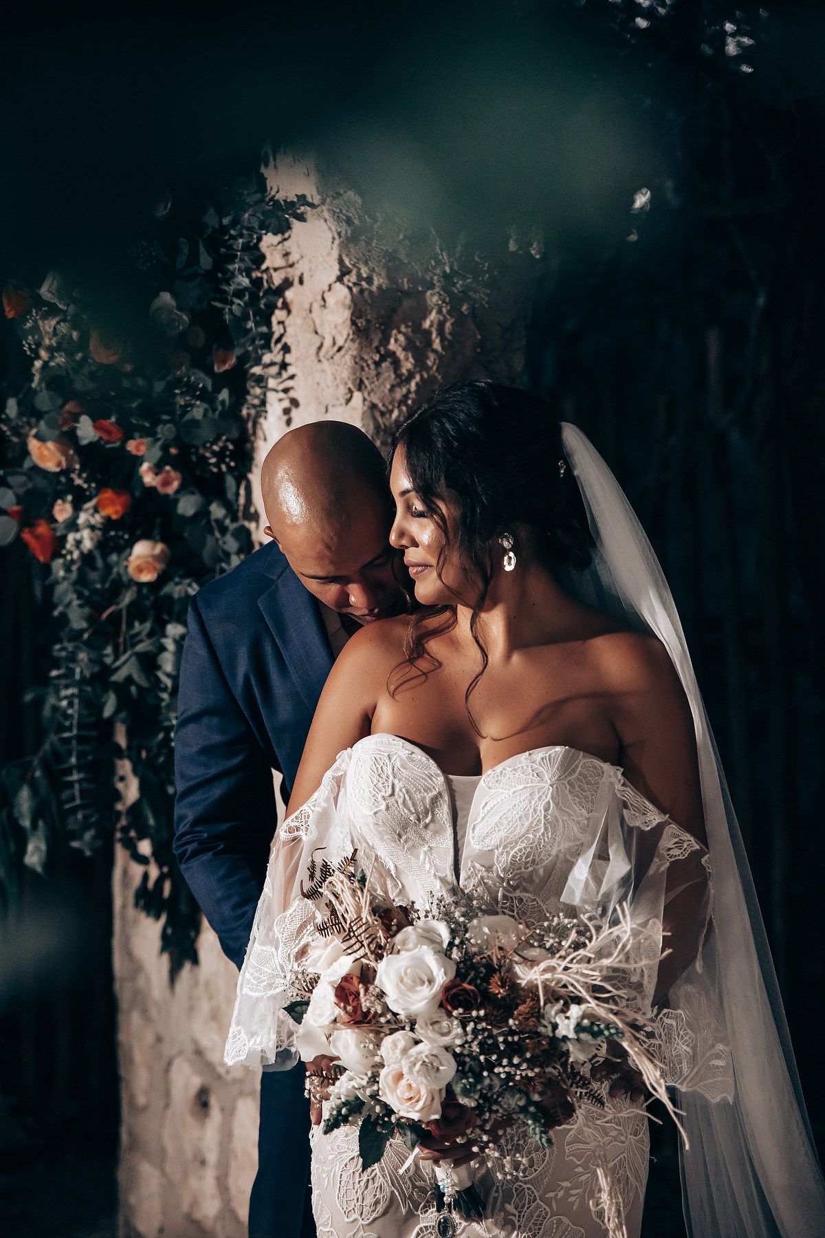 A couple shares an intimate moment with a beautiful floral bouquet during their wedding ceremony.